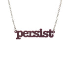 Cassis Persist necklace in typewriter font hanging on a silver chain against a white background.