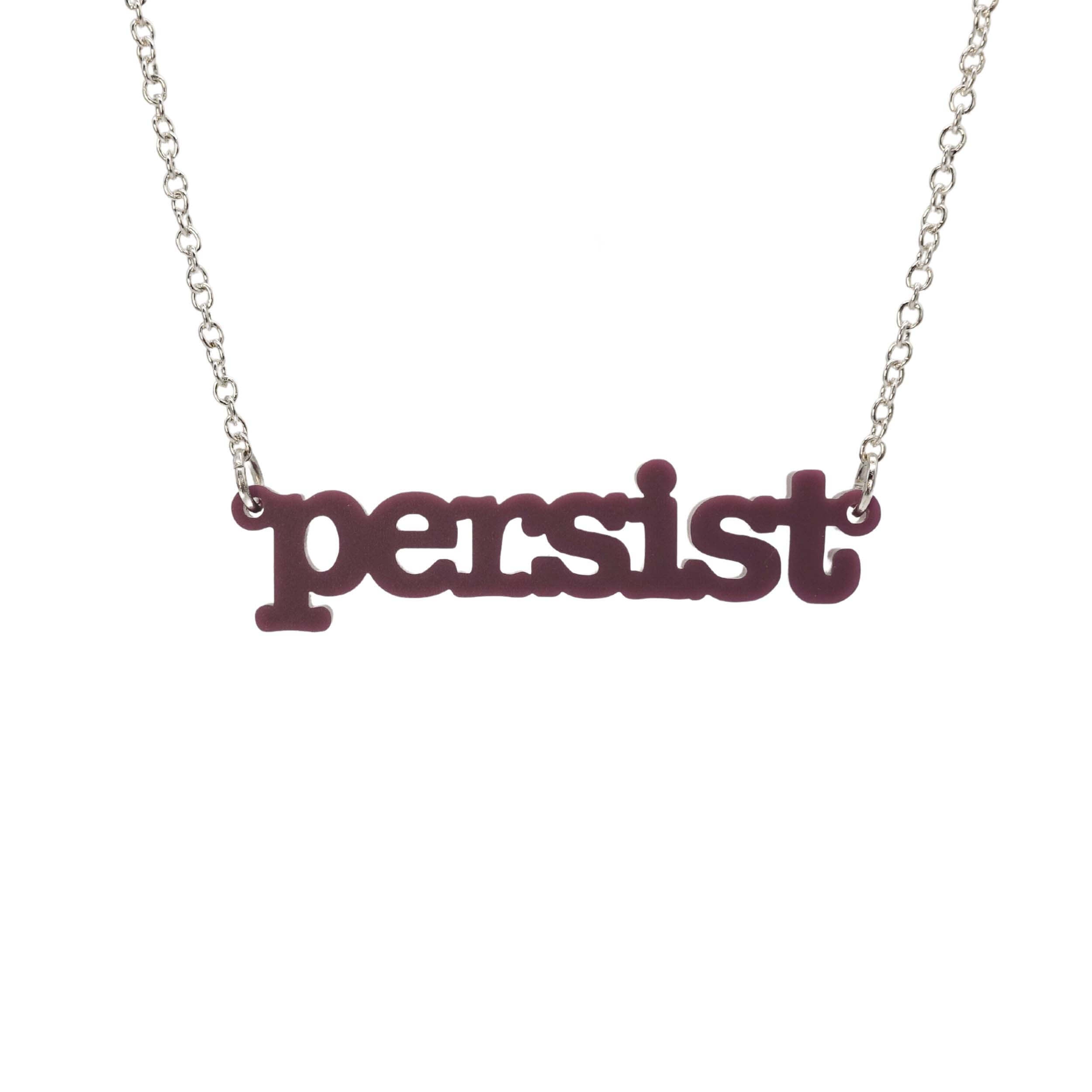 Cassis Persist necklace in typewriter font hanging on a silver chain against a white background.