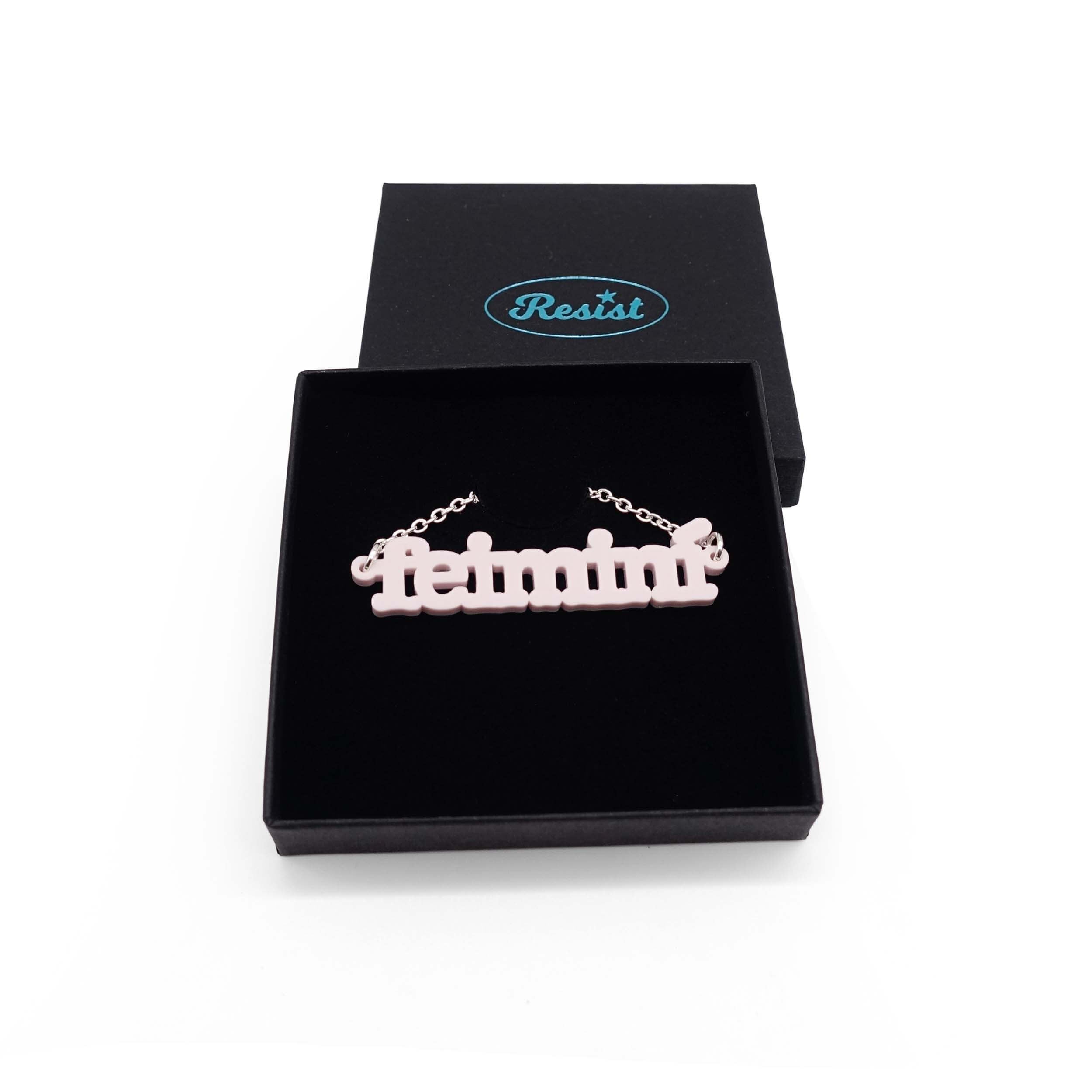 Irish Gaelic Feiminí necklace in chalk pink, shown in a Wear and Resist gift box.