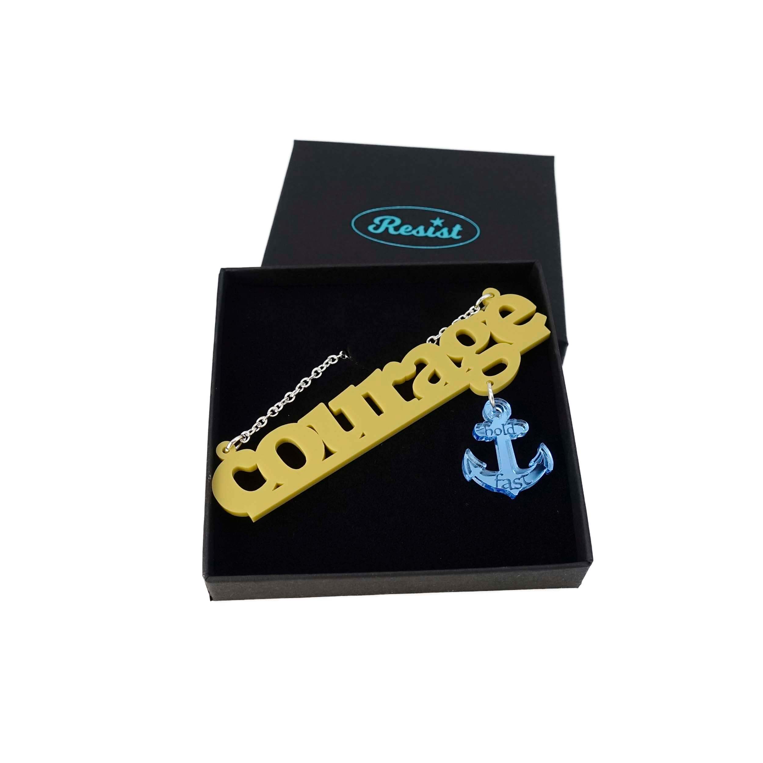 Courage necklace in yellow with sky dangling anchor etched with the words, 'hold fast,' shown on a Wear and Resist gift box.