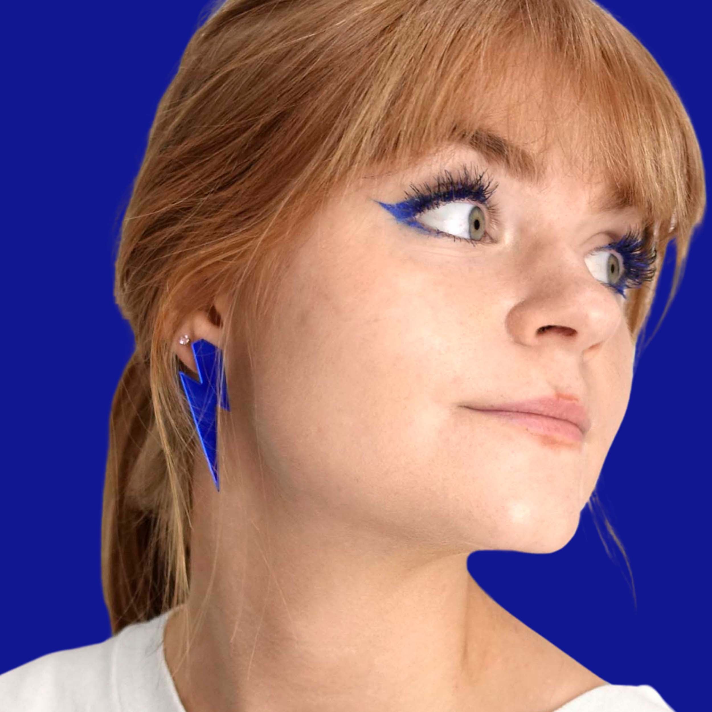 Eliza wears large Lightning Bolt earrings in electric blue mirror.