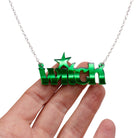Witch necklace in envy green shown hanging against a white background with my hand for size.