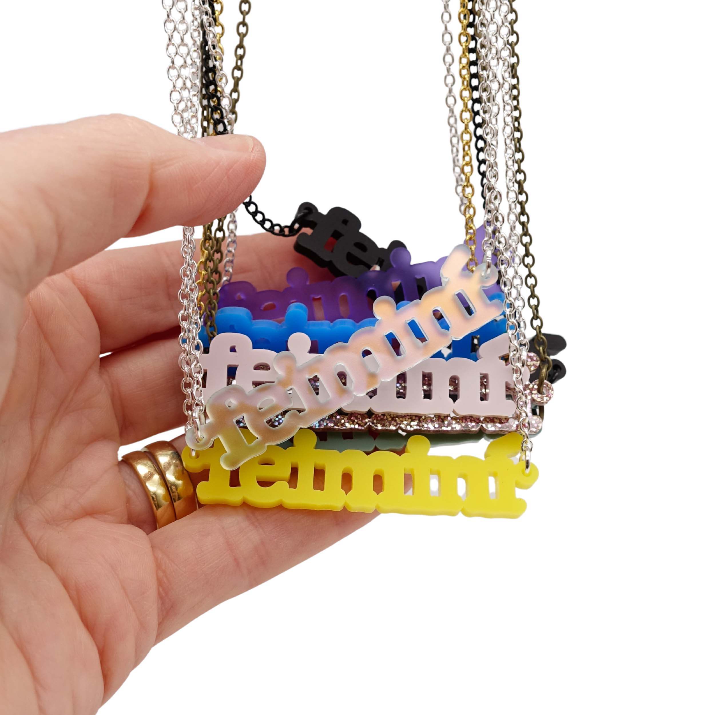 A handful of Irish Gaelic Feiminí necklaces shown hanging together for colour reference and size.