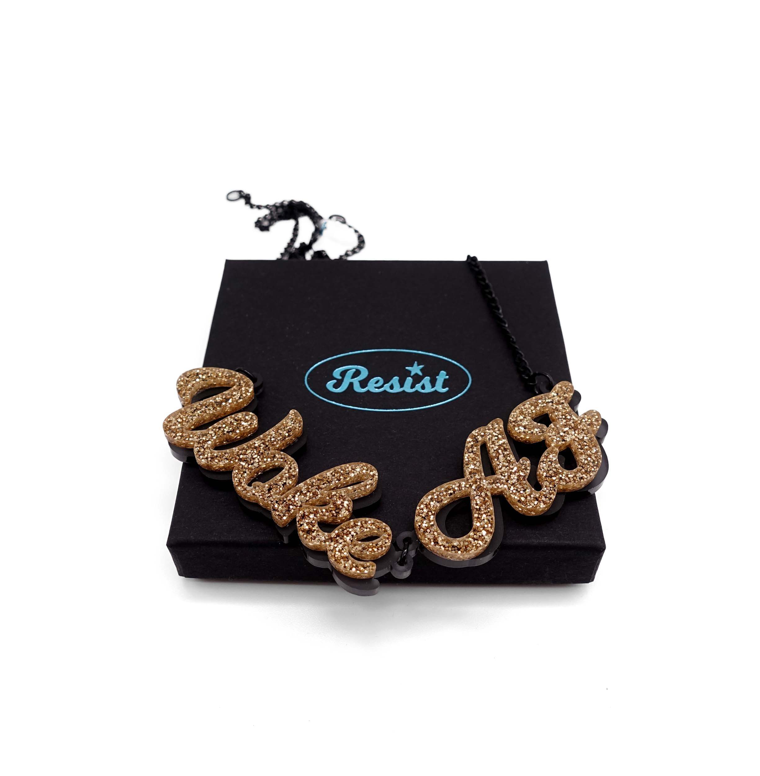 Woke AF necklace in gold glitter shown on a Wear and Resist gift box.