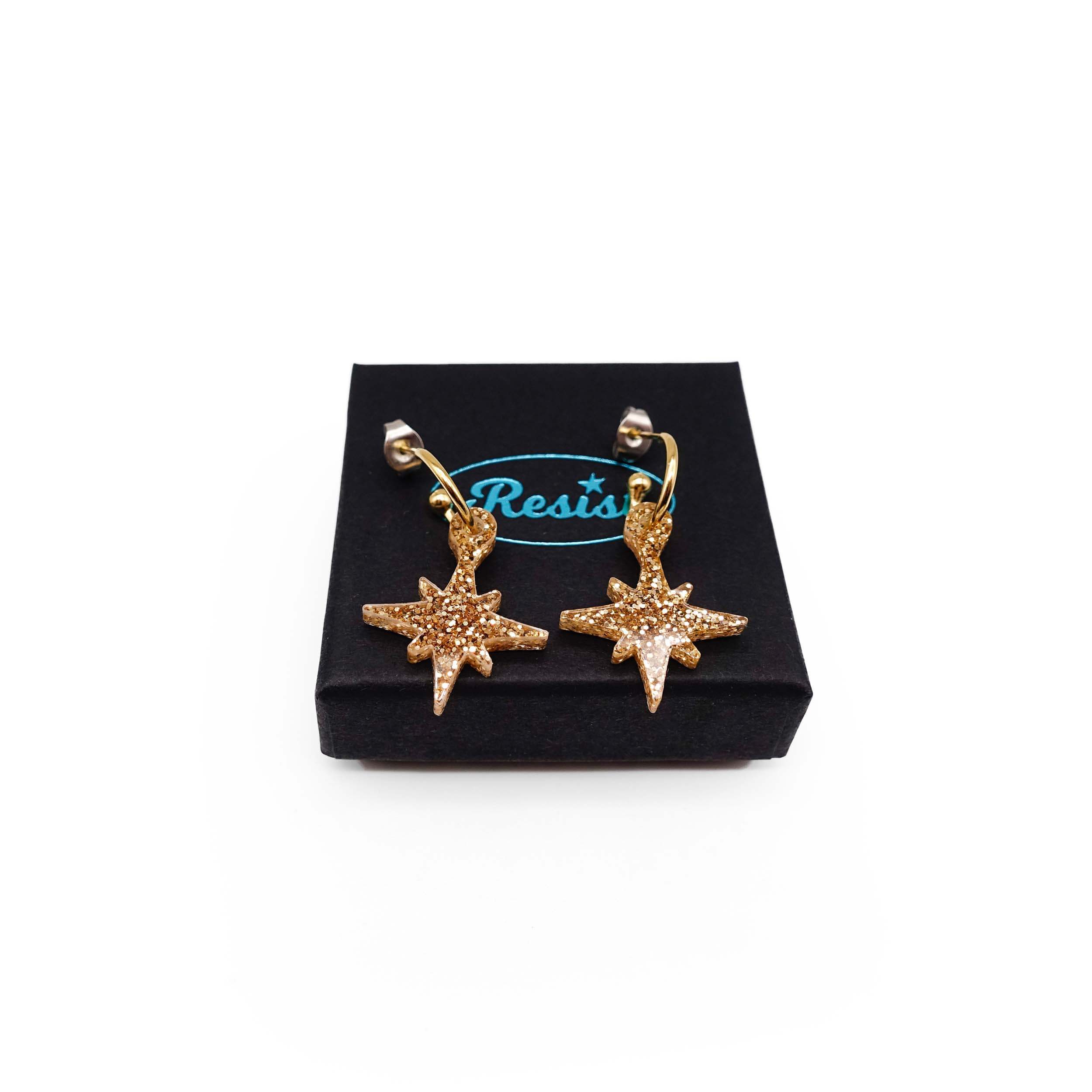 Gold glitter limited edition Festive Vintage Star earrings, shown on a Wear and Resist gift box.