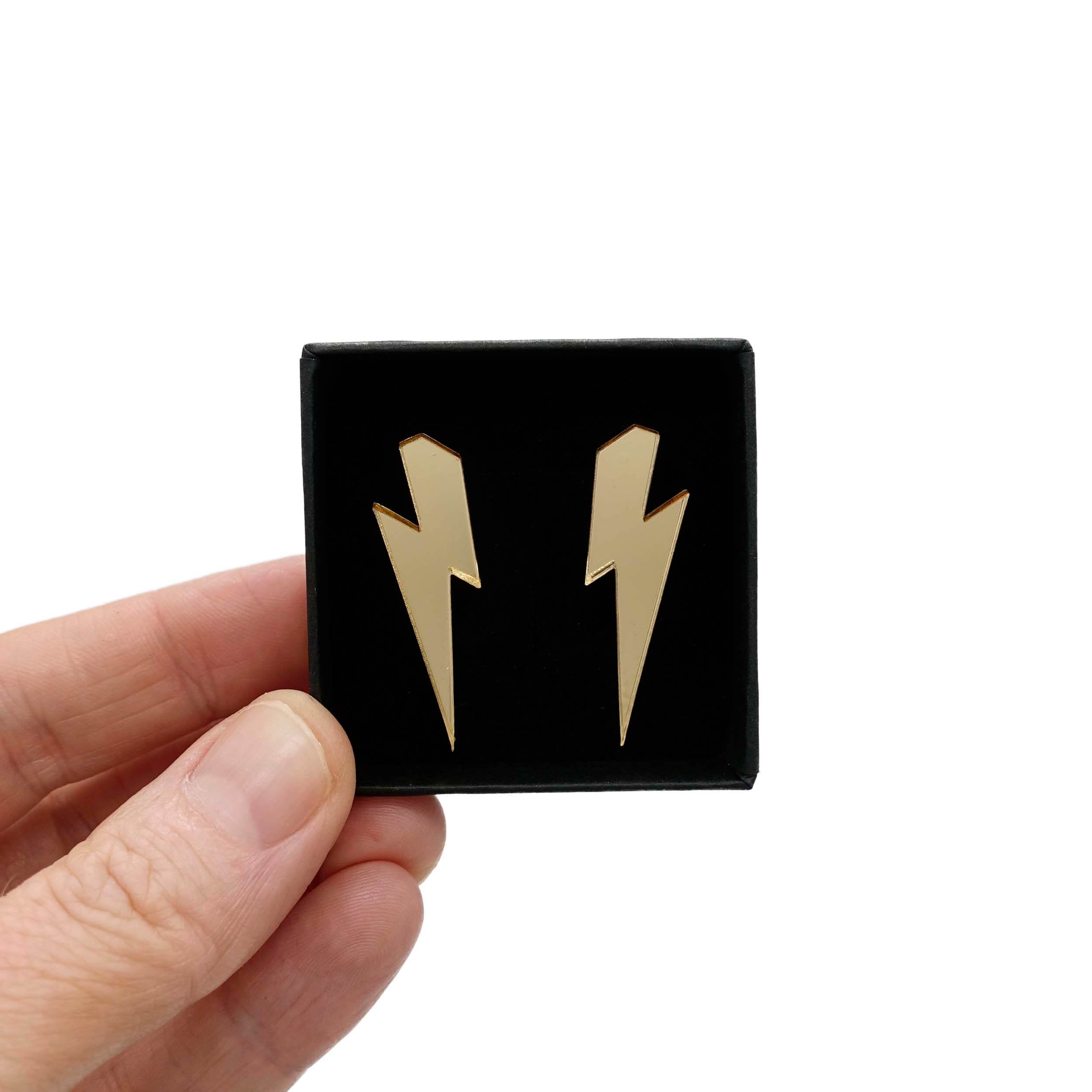 Medium Lightning Bolt earrings in gold mirror, shown held up in a small Wear and Resist gift box.