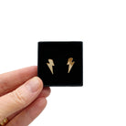 Tiny Lightning Bolt earrings in gold mirror, shown held up in a small Wear and Resist gift box.