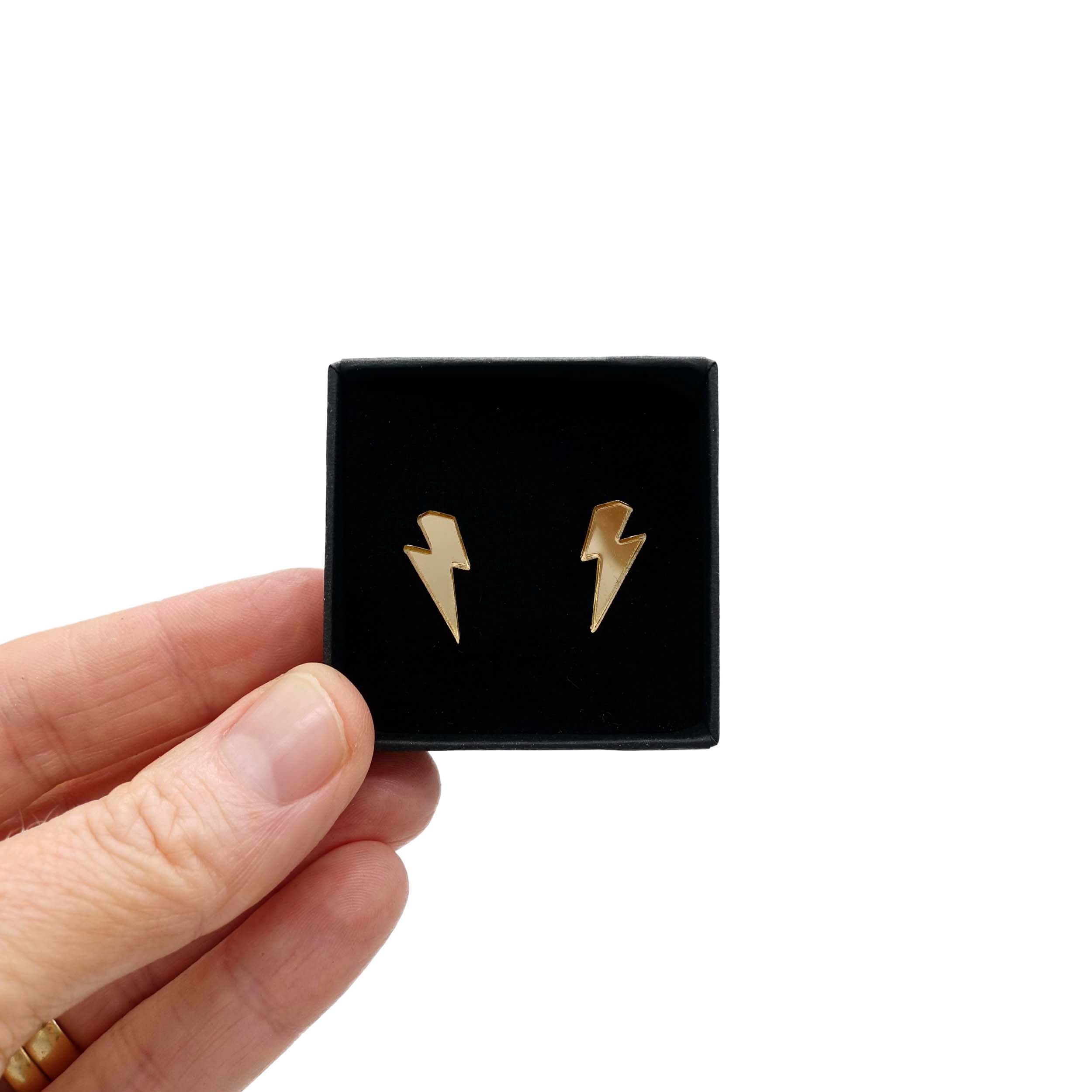 Tiny Lightning Bolt earrings in gold mirror, shown held up in a small Wear and Resist gift box.