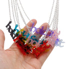 A group of Hold Fast necklaces in seven different frost colours, shown hanging together with a hand for scale.
