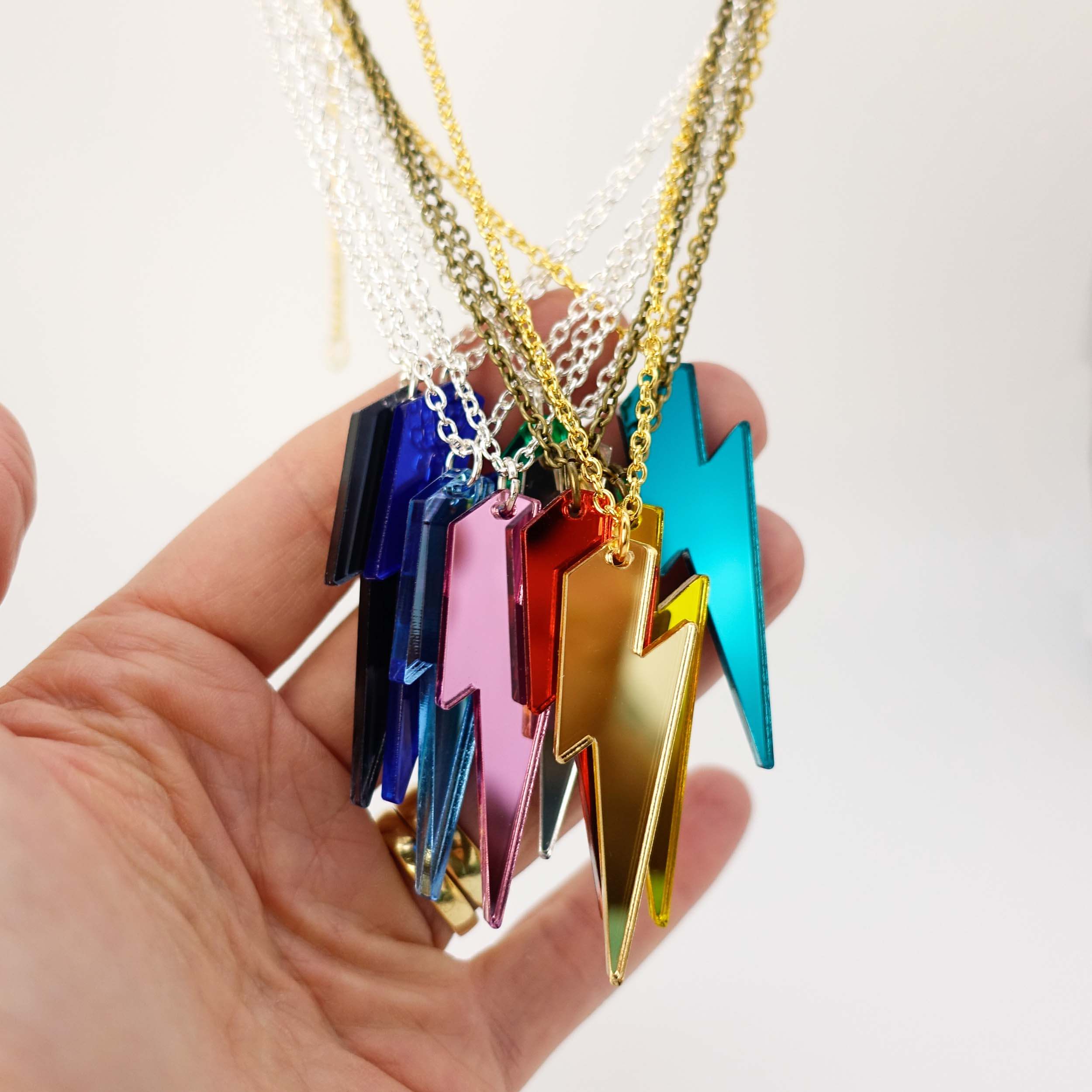 A group of LIghtning Bolt necklaces shown hanging with my hand for scale.
