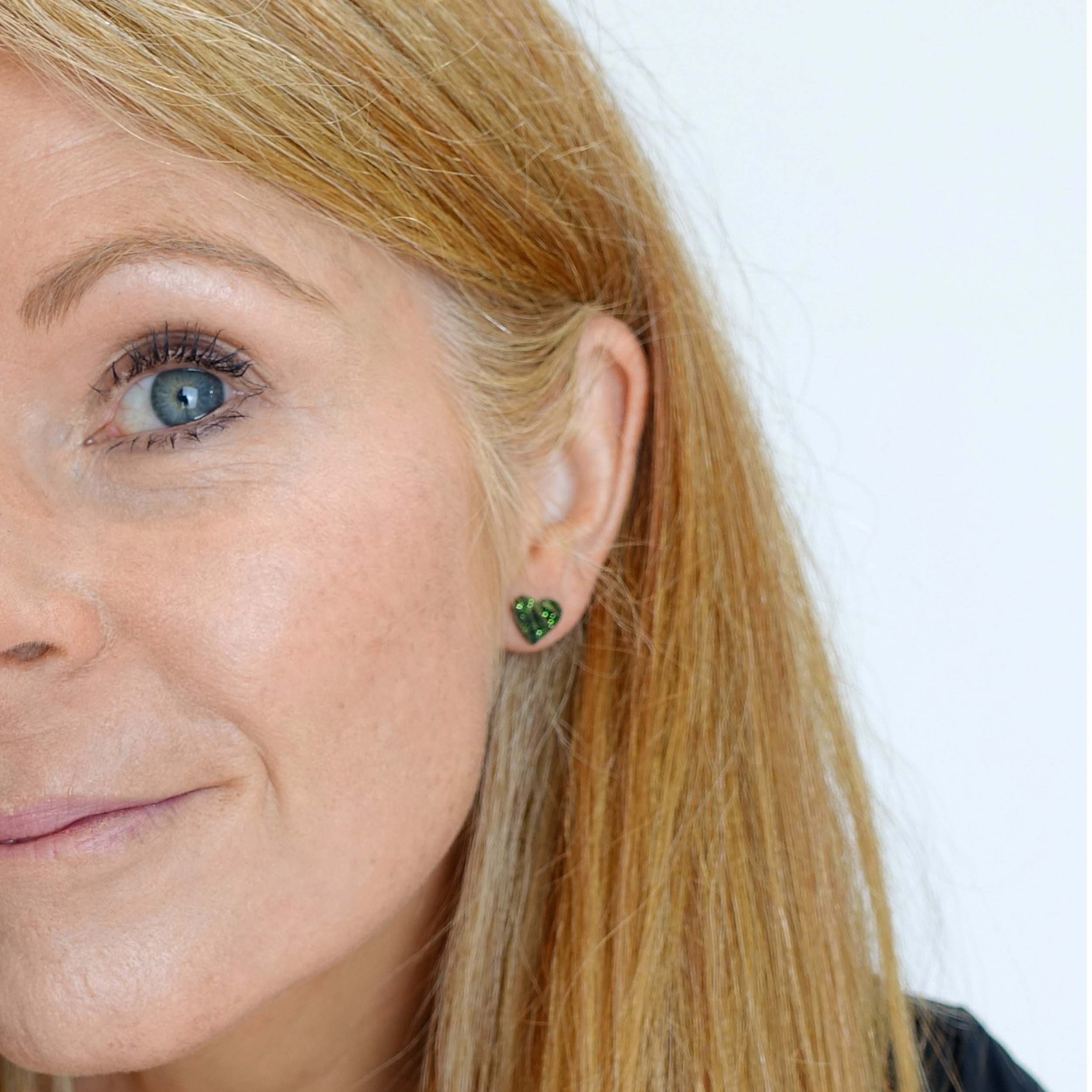 Sarah wears little heart earrings in moss glitter.