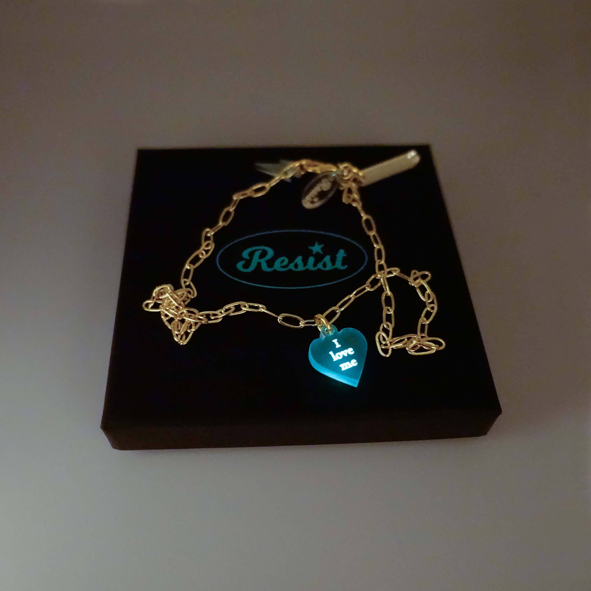 'I love me' glow in the dark choker and bracelet on a gold plated delicate paperclip chain, shown in a Wear and Resist gift box glowing in the dark.