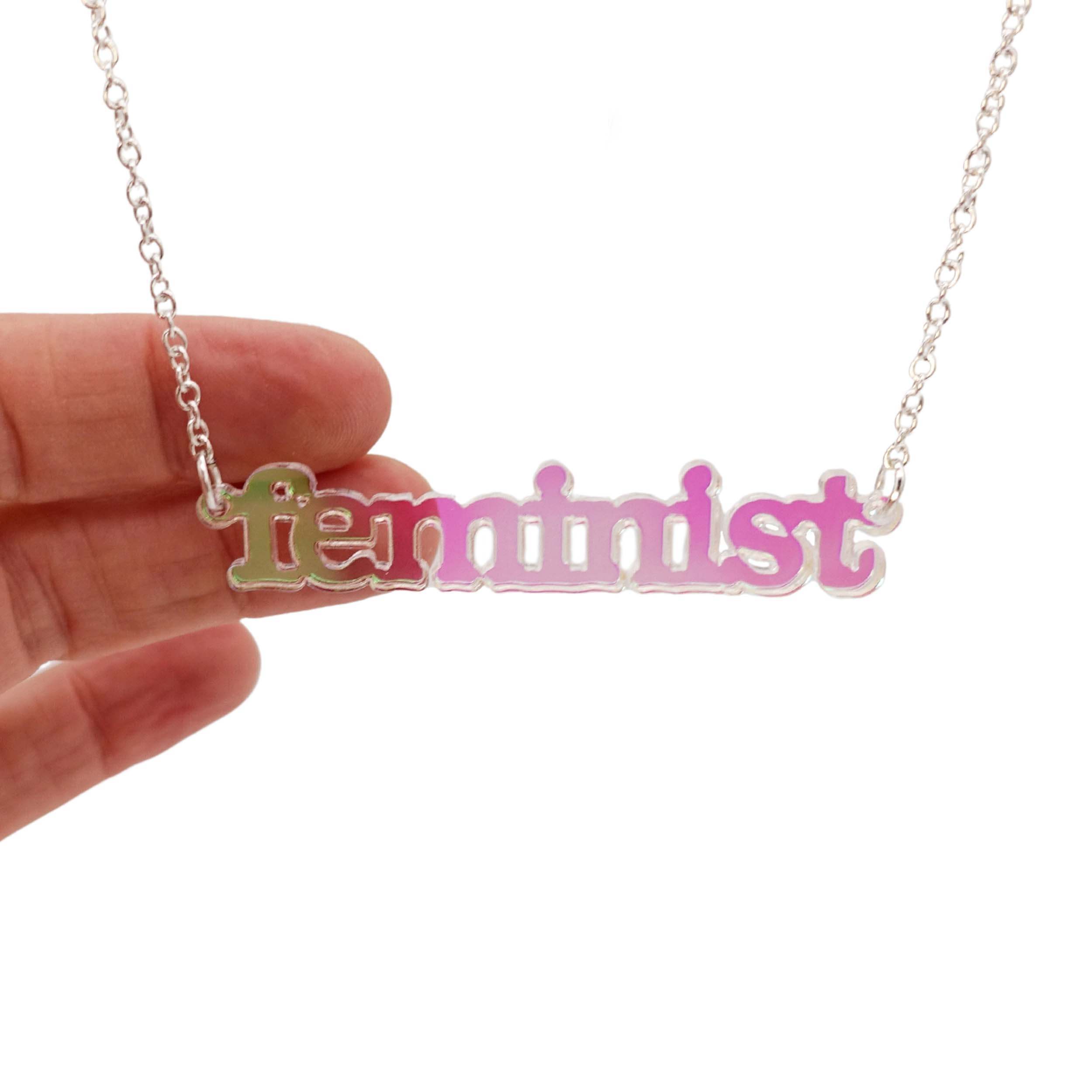 Iridescent Feminist necklace shown hanging on a white background.