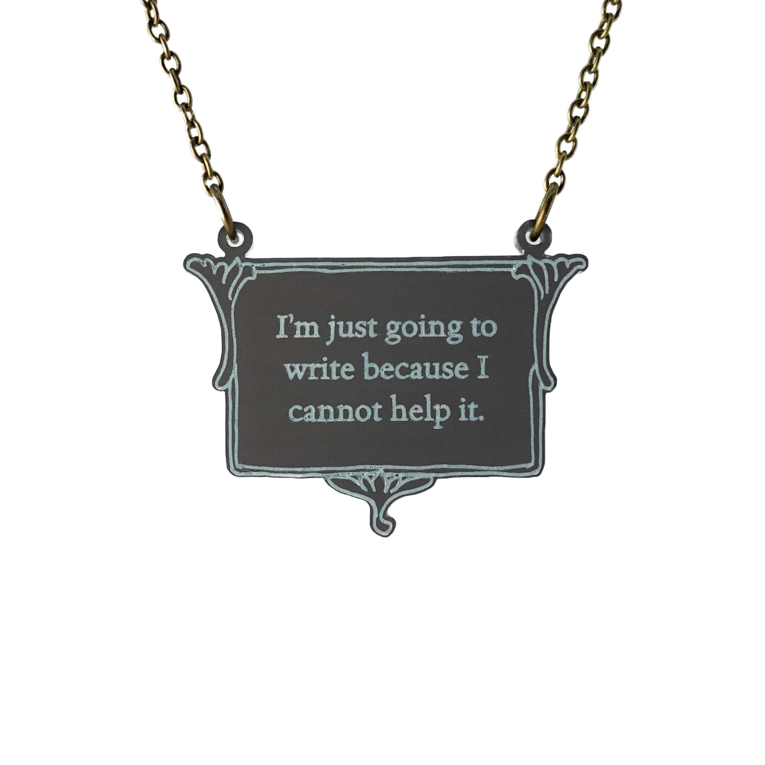 A vintage style slate frost necklace etched with Charlotte Brontë's words in glow-in-the-dark pigment that says, 'I'm just going to write because I cannot help it.' It is shown on an antique gold chain hanging against a white background.