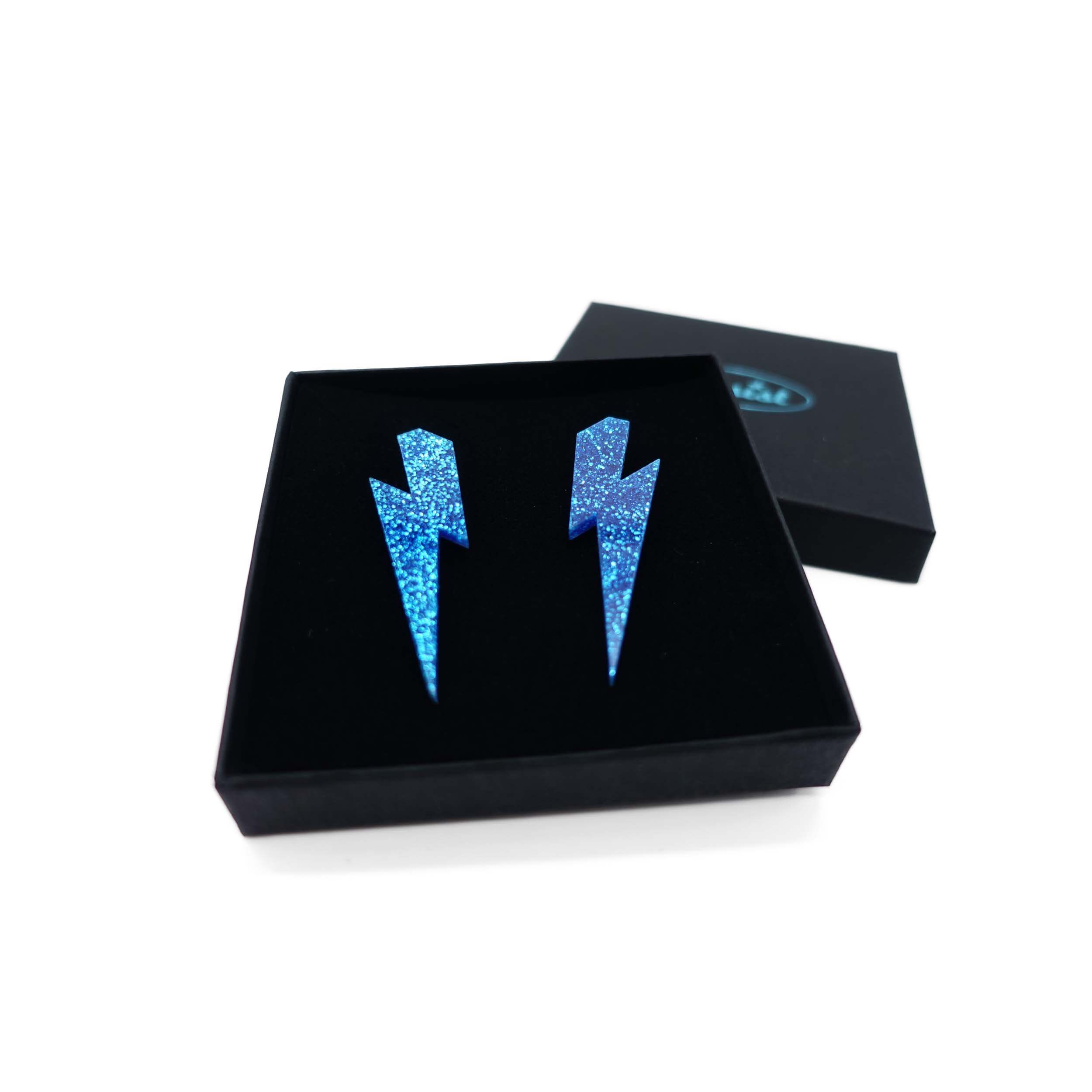 Large Lightning Bolt earrings in blue glitter, shown in a Wear and Resist gift box.
