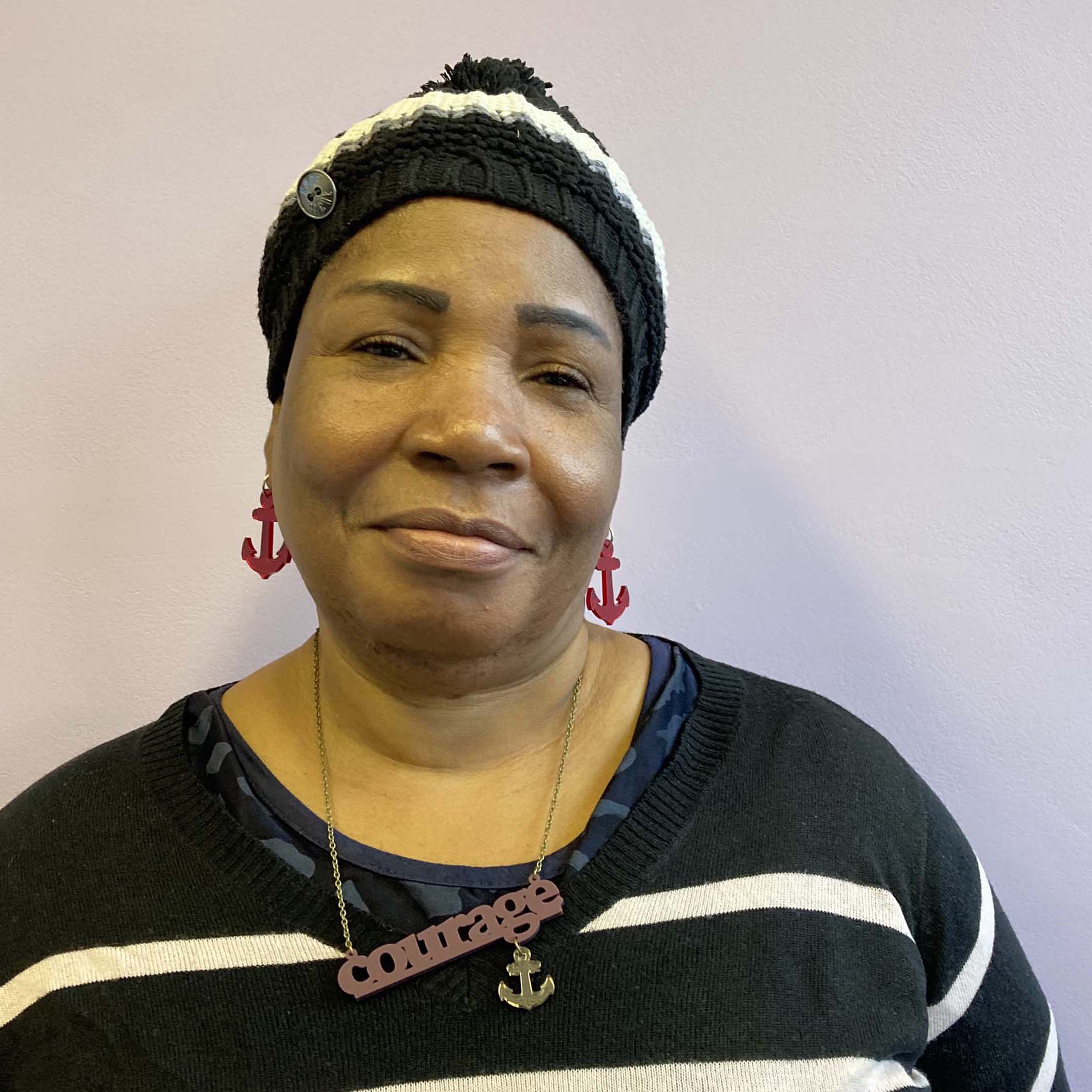 A member of Women for Refugee Women models the Courage and Hold Fast anchor earrings in ruby red and a Courage necklace with Hold Fast anchor in carmine and gold. £2 from everything in the Courage Collection goes to Women for Refugee Women.