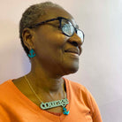 A member of Women for Refugee Women wears medium teal Courage and Hold Fast ancor earrings and a duck egg green Courage necklace from The Courage Collection. £2 from everything in this collection goes to this incredible charity.