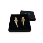 Large Lightning Bolt earrings in gold glitter, shown in a Wear and Resist gift box.
