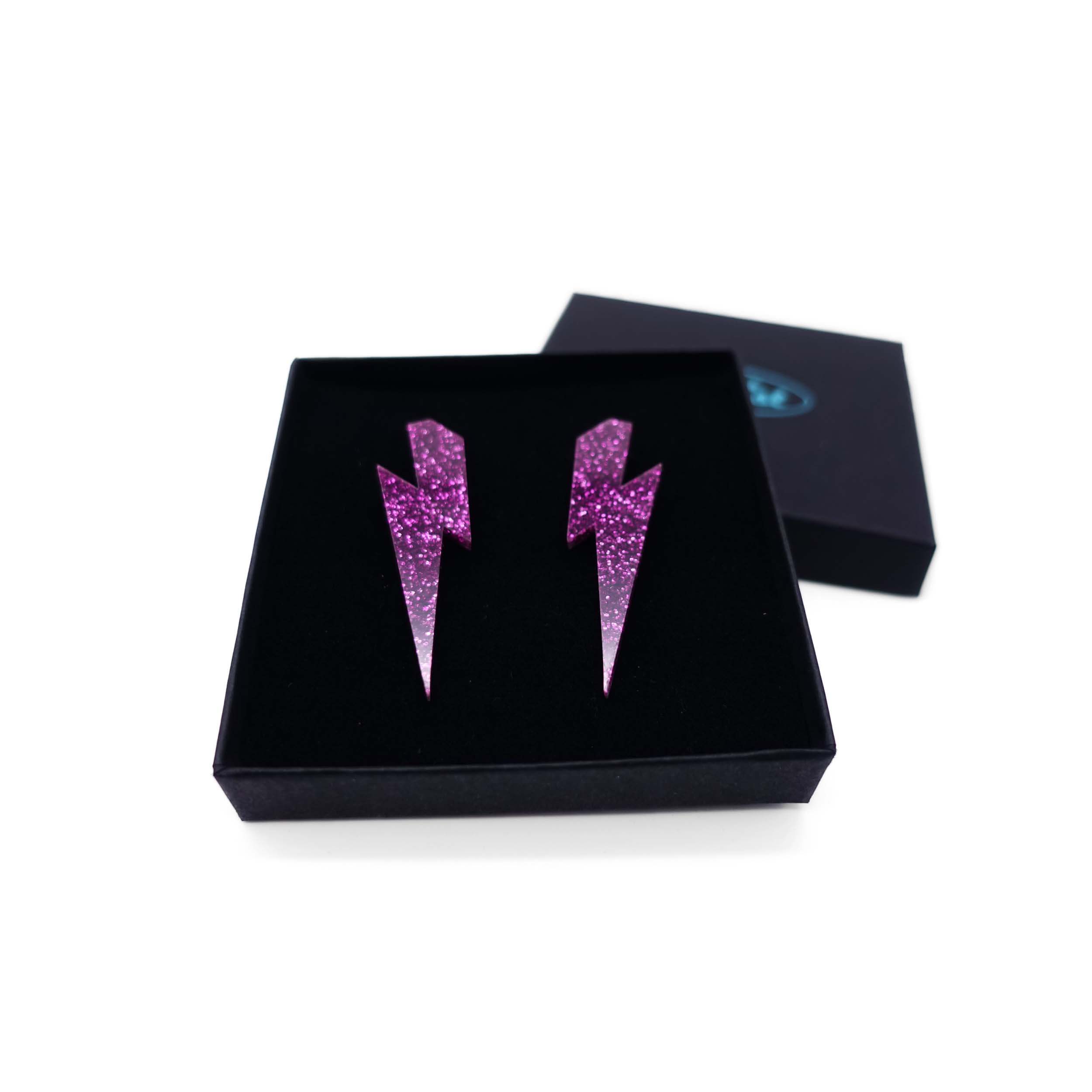 Large Lightning Bolt earrings in purple glitter, shown in a Wear and Resist gift box.