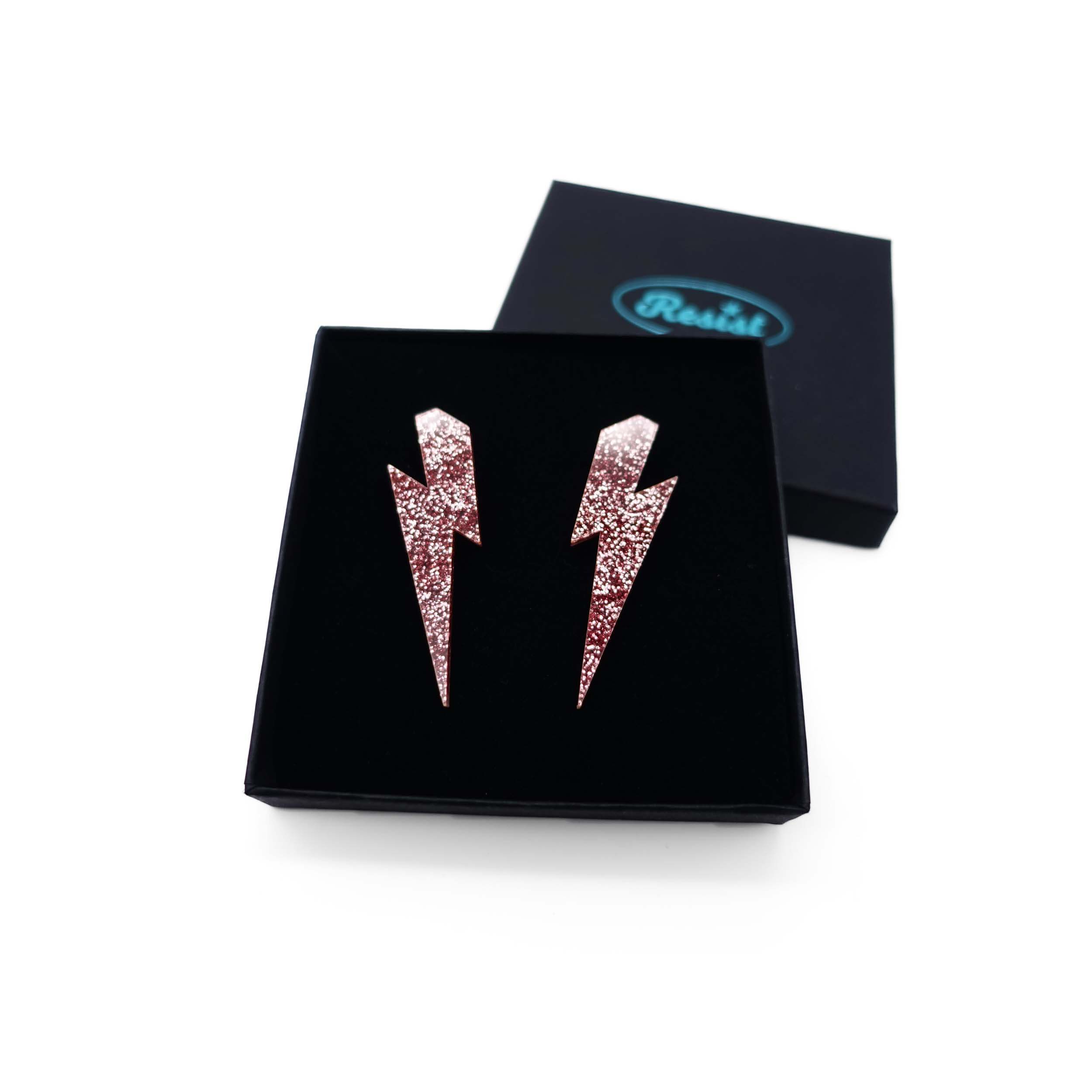 Large Lightning Bolt earrings in rose glitter, shown in a Wear and Resist gift box.