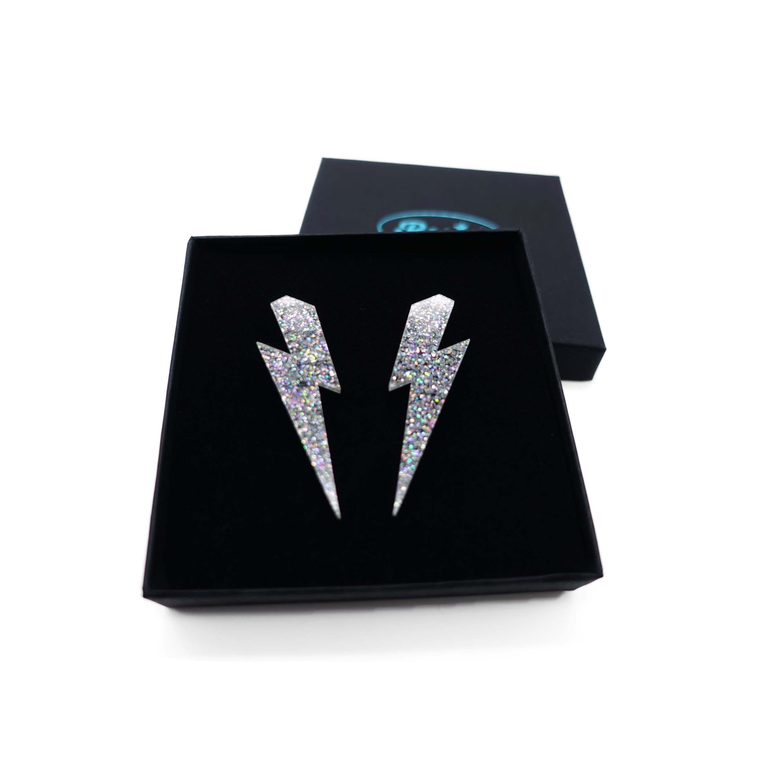 Large Lightning Bolt earrings in silver glitter, shown in a Wear and Resist gift box.