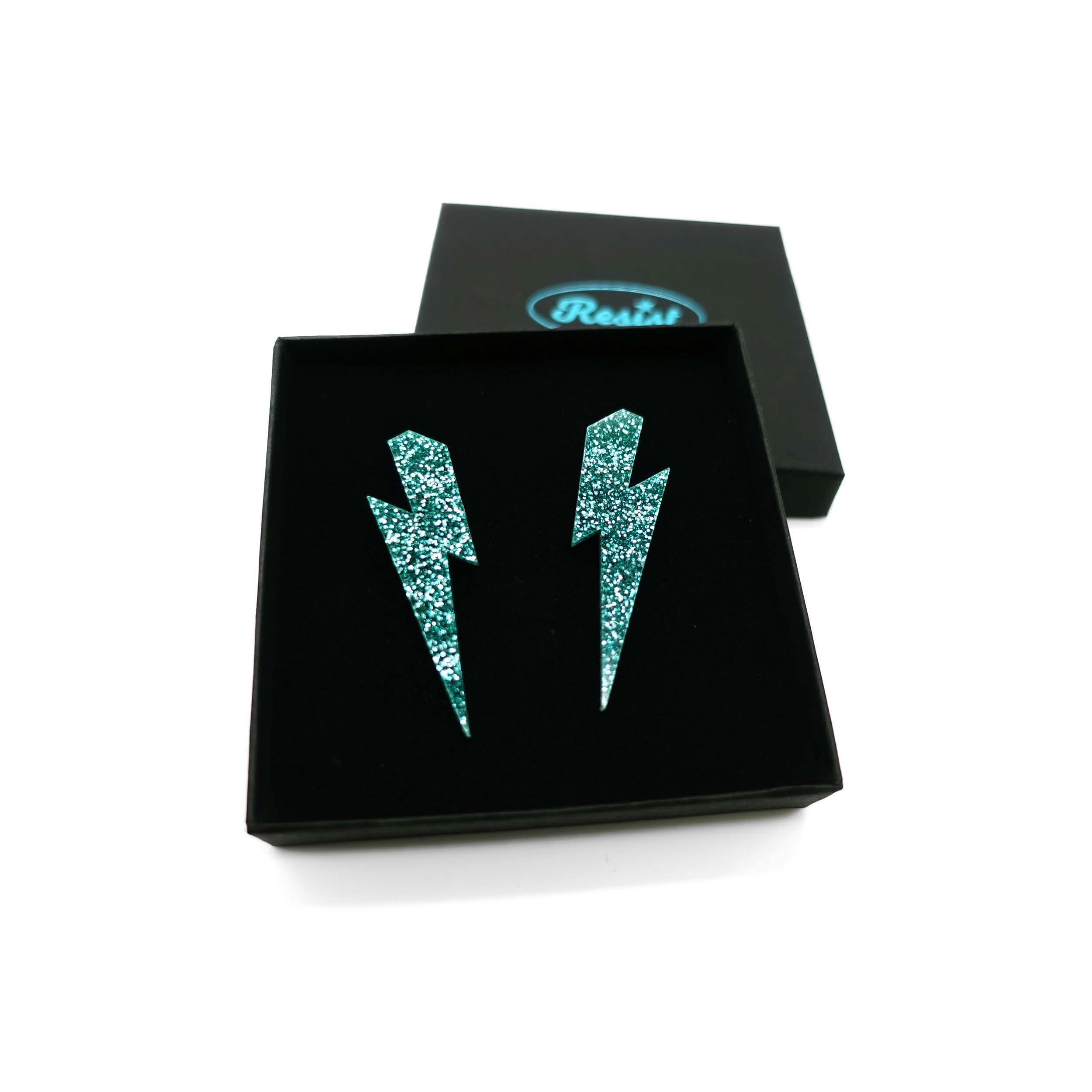 Large Lightning Bolt earrings in teal glitter, shown in a Wear and Resist gift box.