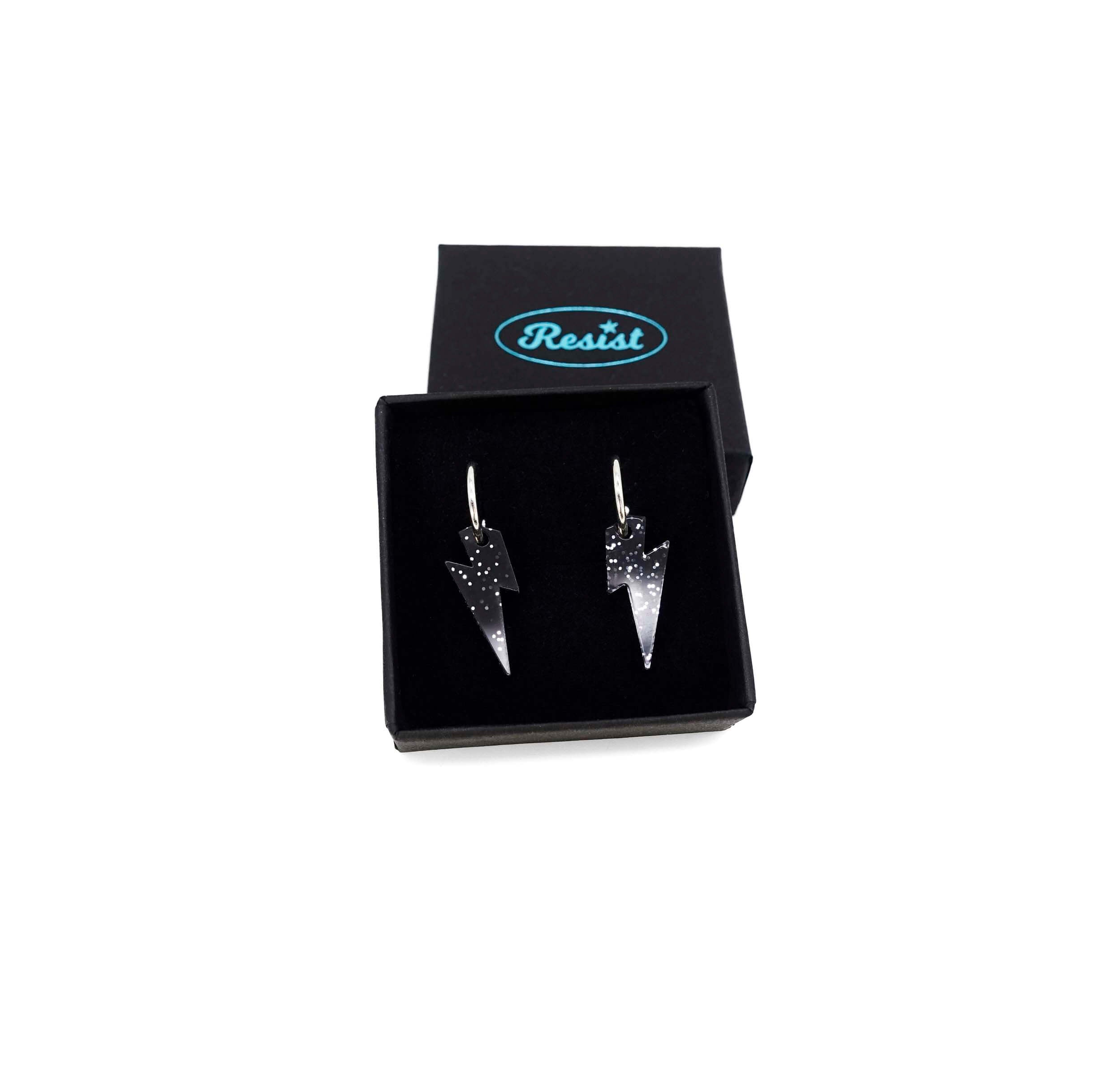 Lightning bolt hoop earrings in black glitter on silver-plated hoops, shown  in a small Wear and Resist gift box.