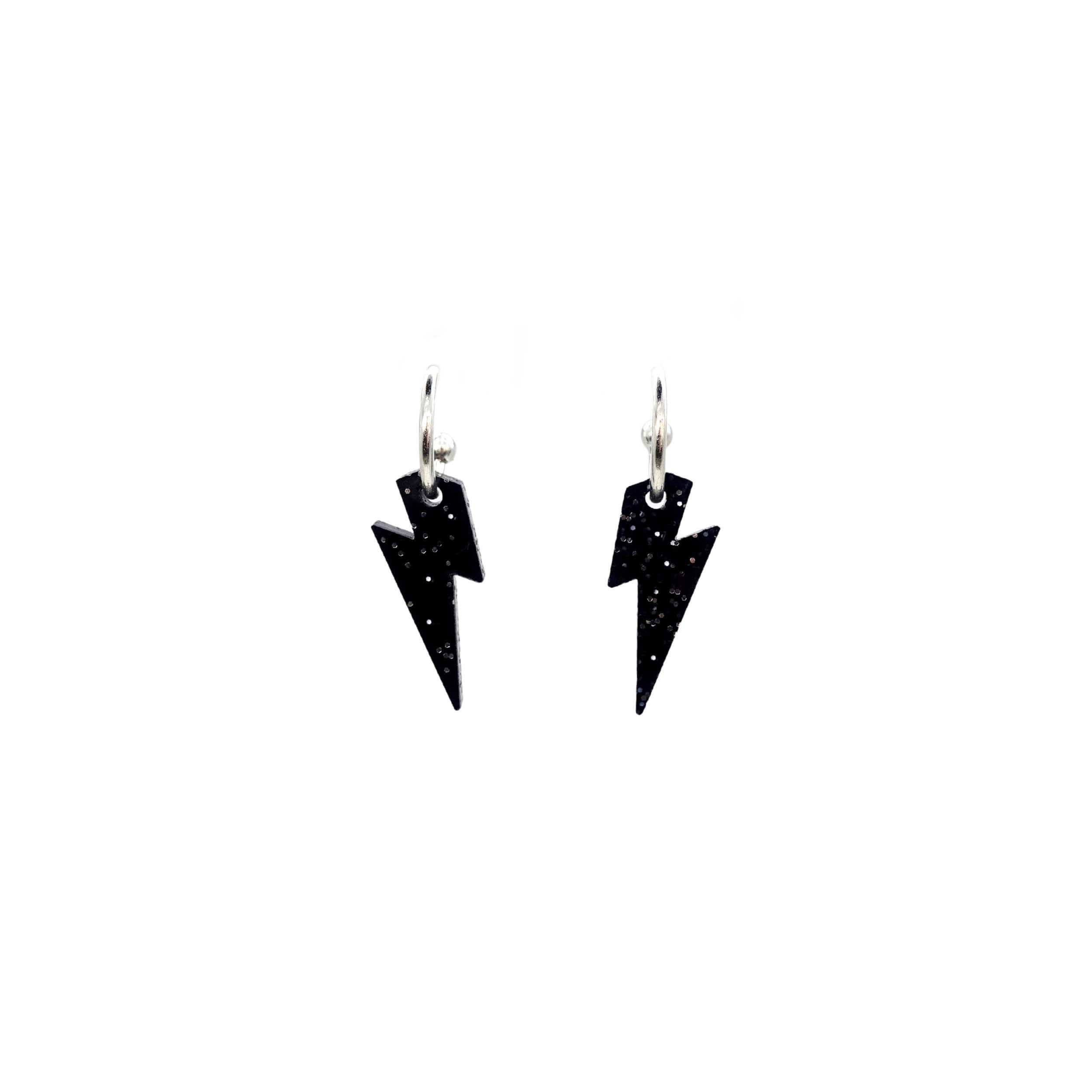 Lightning bolt hoop earrings in black glitter on silver-plated hoops, shown hanging against a white background.