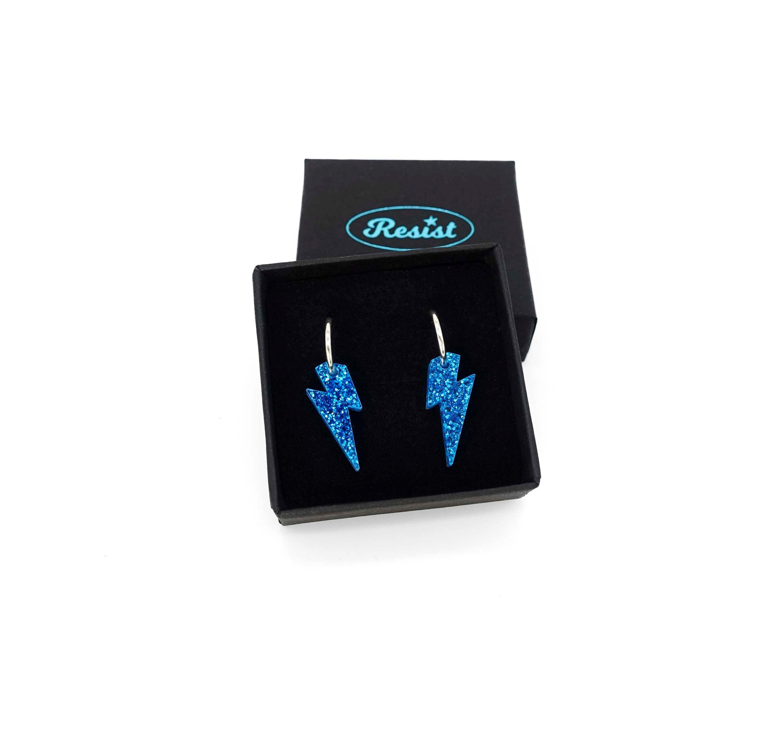 Lightning bolt hoop earrings in blue glitter on silver-plated hoops, shown in a Wear and Resist gift box.