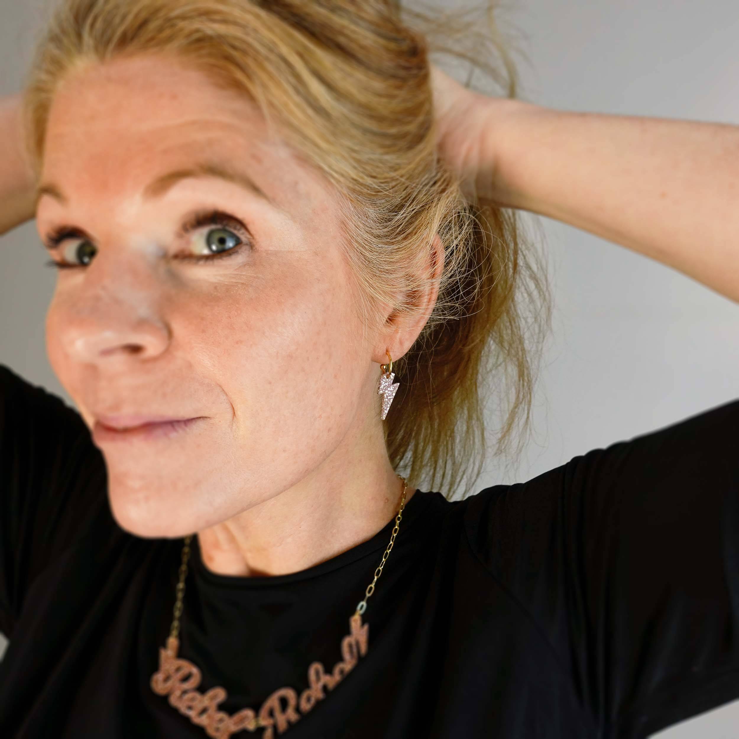 Sarah Day wears Lightning bolt hoop earrings in pink fizz glitter with a matching Rebel Rebel necklace.
