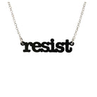 Matte black Resist necklace in typewriter font hanging on a silver chain against a white background.