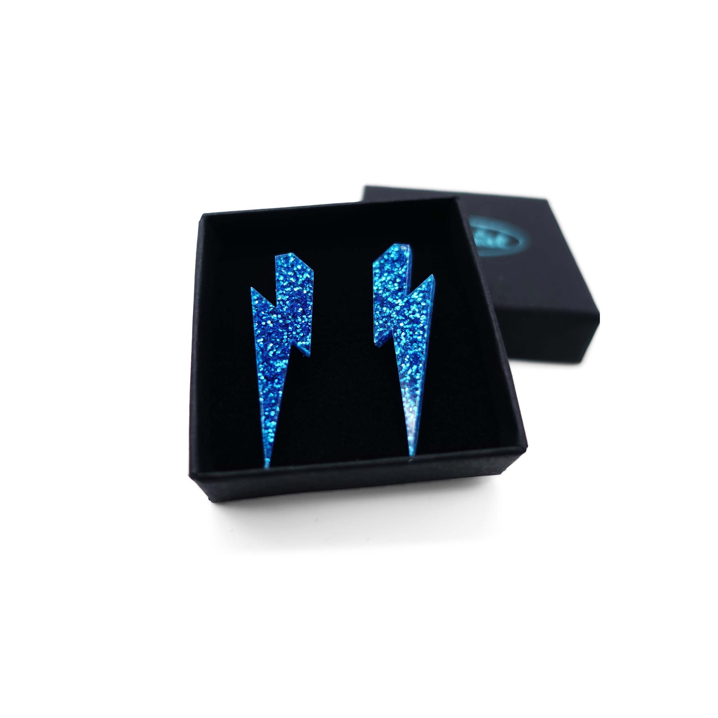Medium Lightning bolt earrings in blue glitter, shown in a Wear and Resist gift box.
