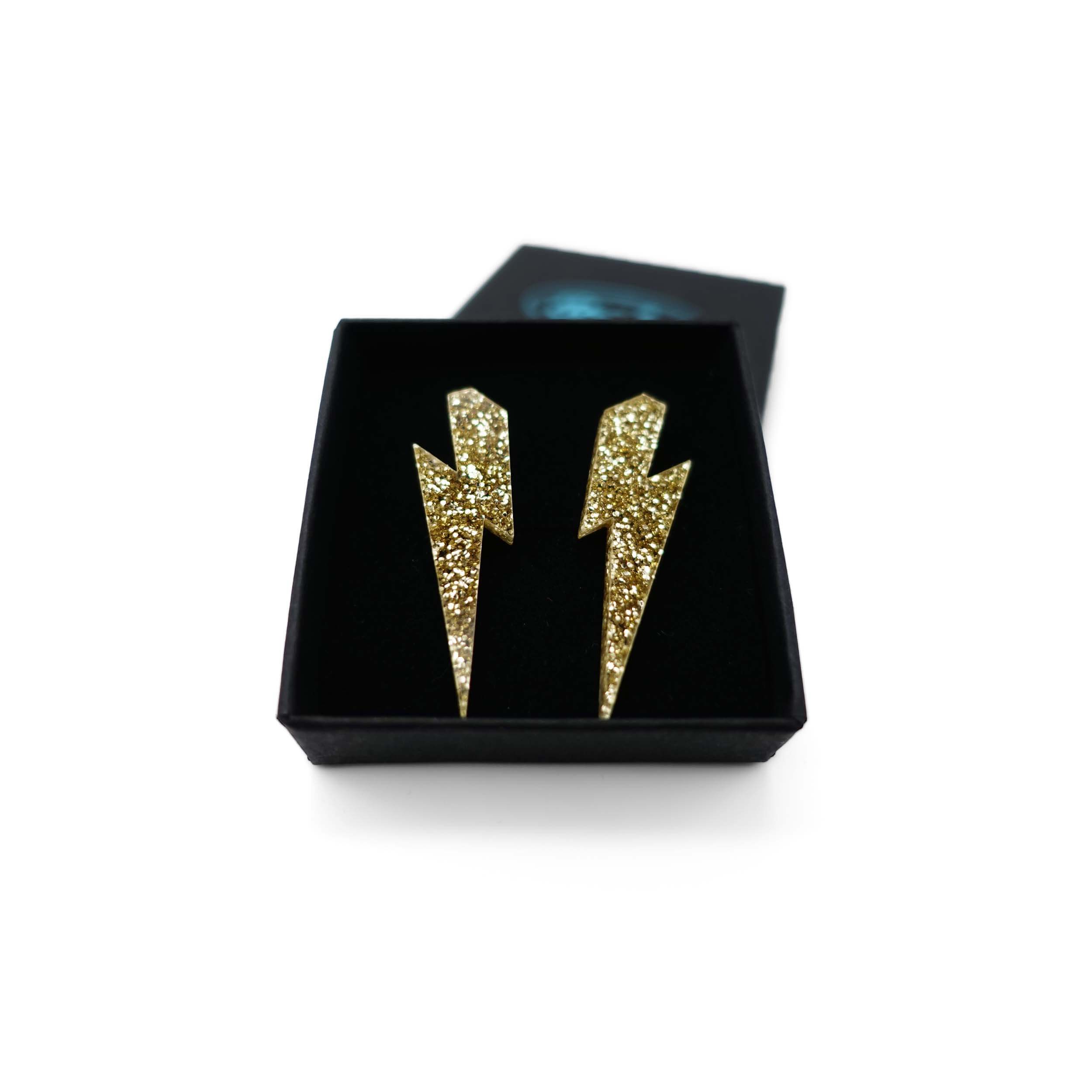 Medium Lightning bolt earrings in gold glitter, shown in a Wear and Resist gift box.