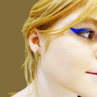 Eliza wears medium Lightning bolt earrings in gold glitter.