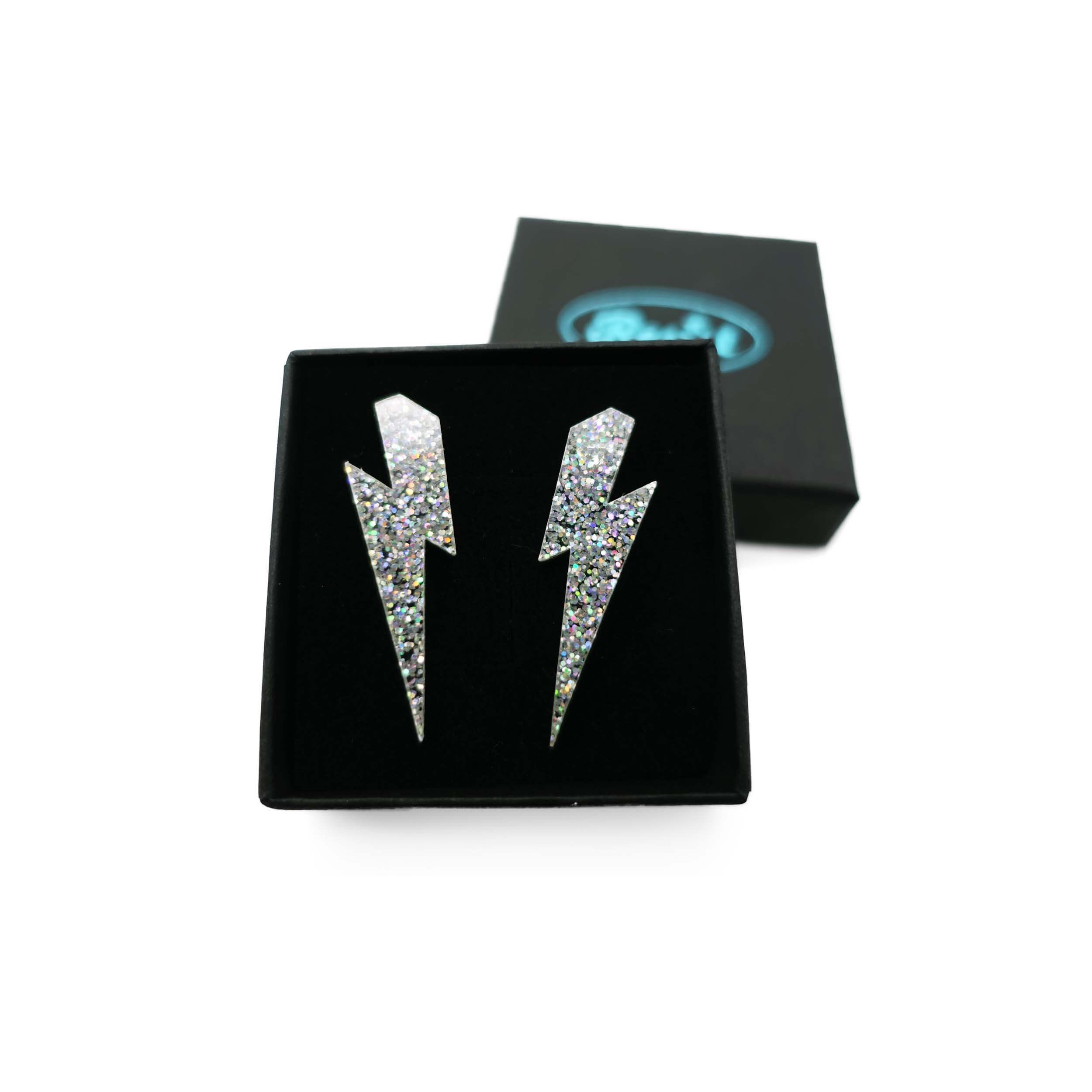 Medium Lightning bolt earrings in silver glitter, shown in a Wear and Resist gift box.