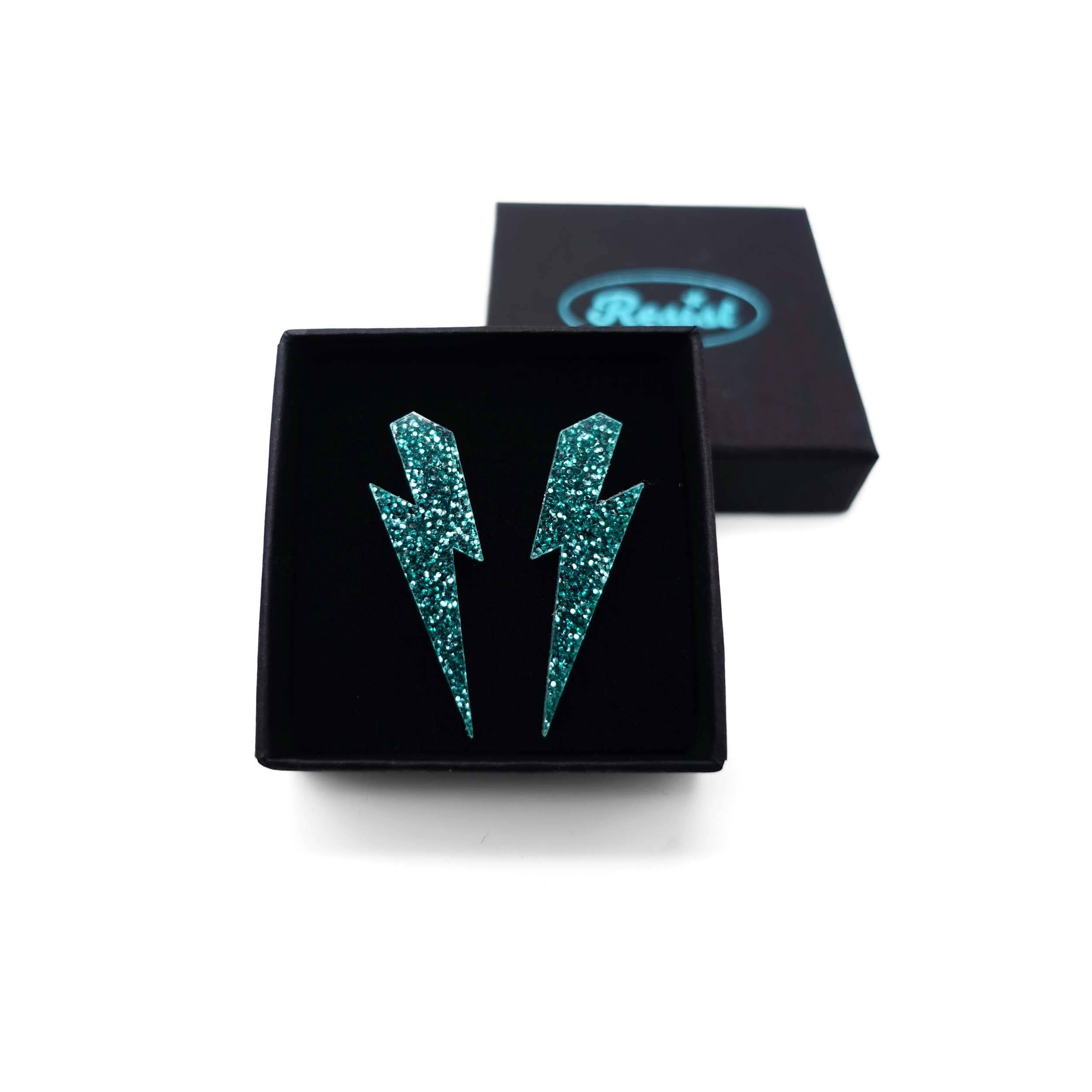 Medium Lightning Bolt earrings in teal glitter, shown in a small Wear and Resist gift box.