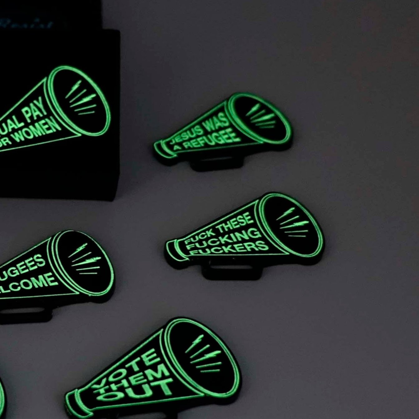 F*ck these F*cking F*ckers Megaphone brooch, shown glowing in the dark.