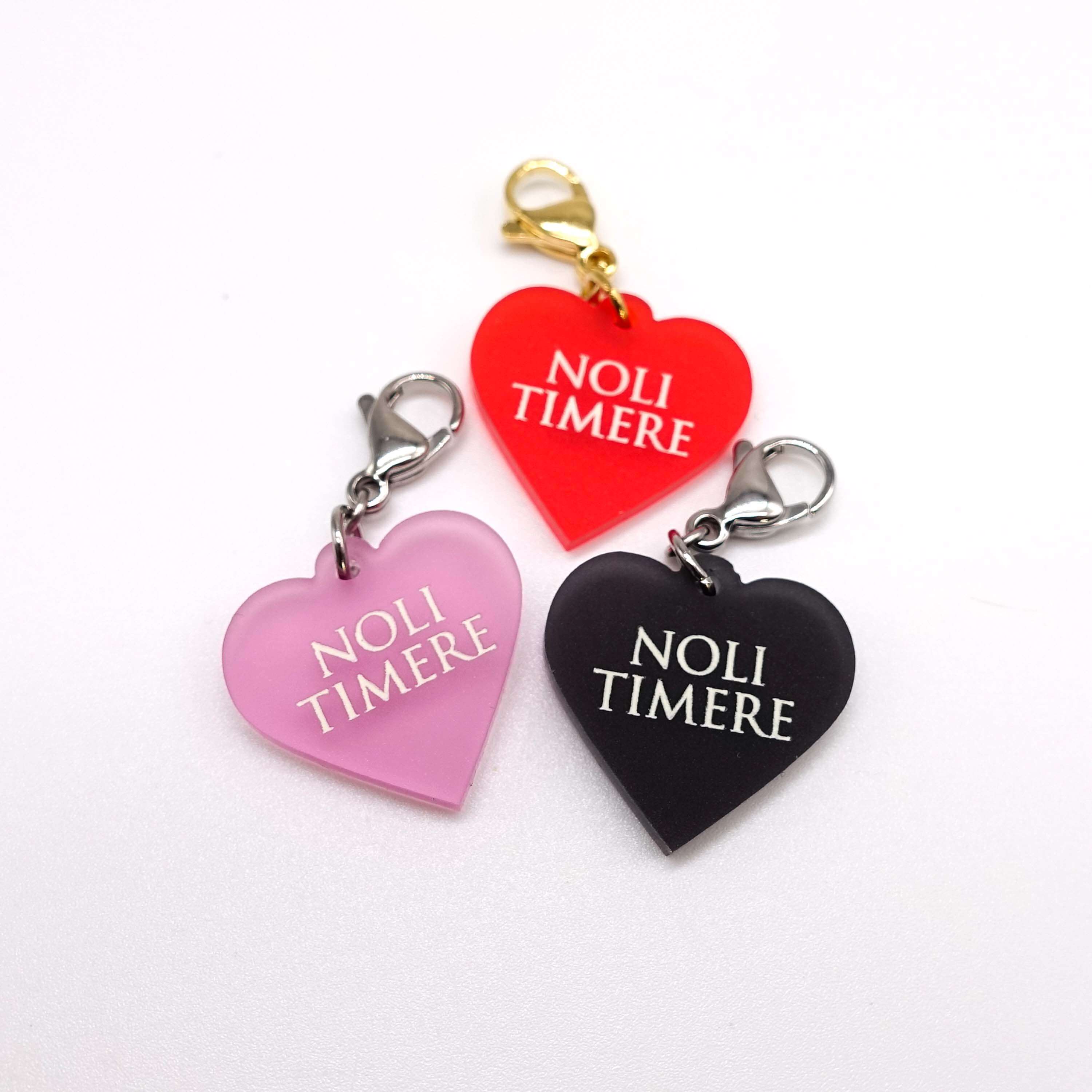 Heart charms etched and hand-painted with the words Noli Timere in glow in the dark pigment.