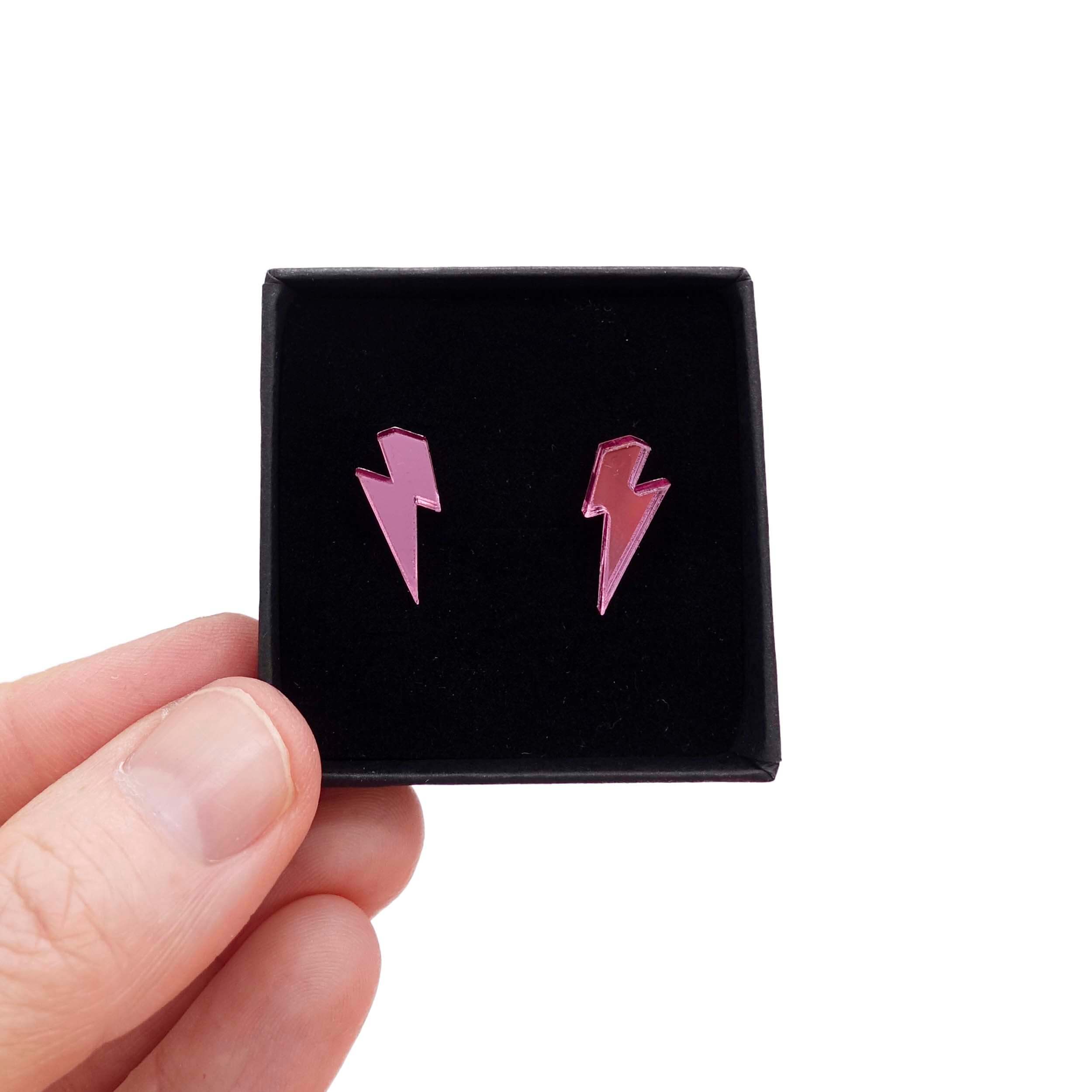 Tiny Lightning Bolt earrings in pink mirror, shown held up in a small Wear and Resist gift box.