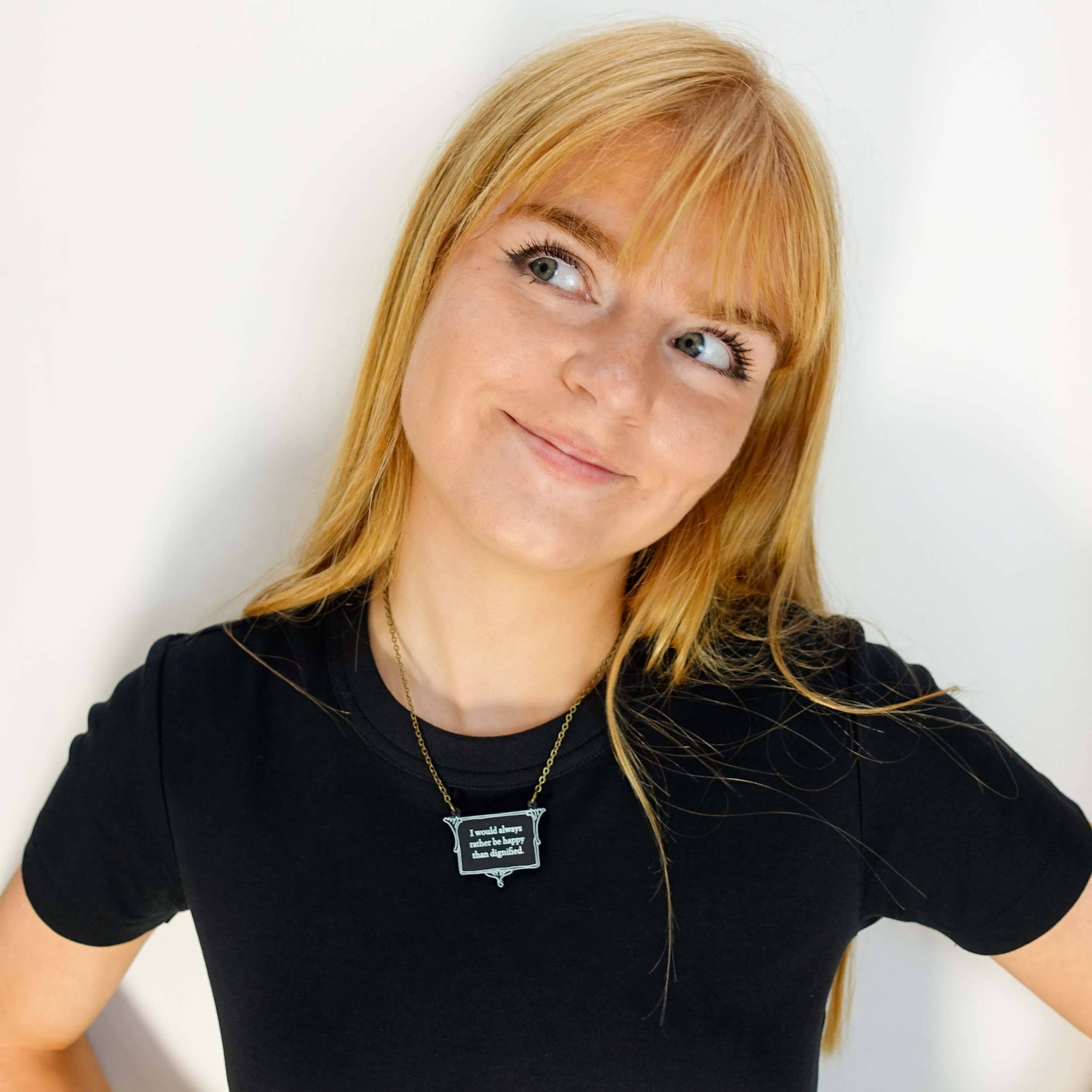Eliza wears a vintage style slate necklace etched with the words of Jane Eyre 'I would always rather be happy than dignified'.