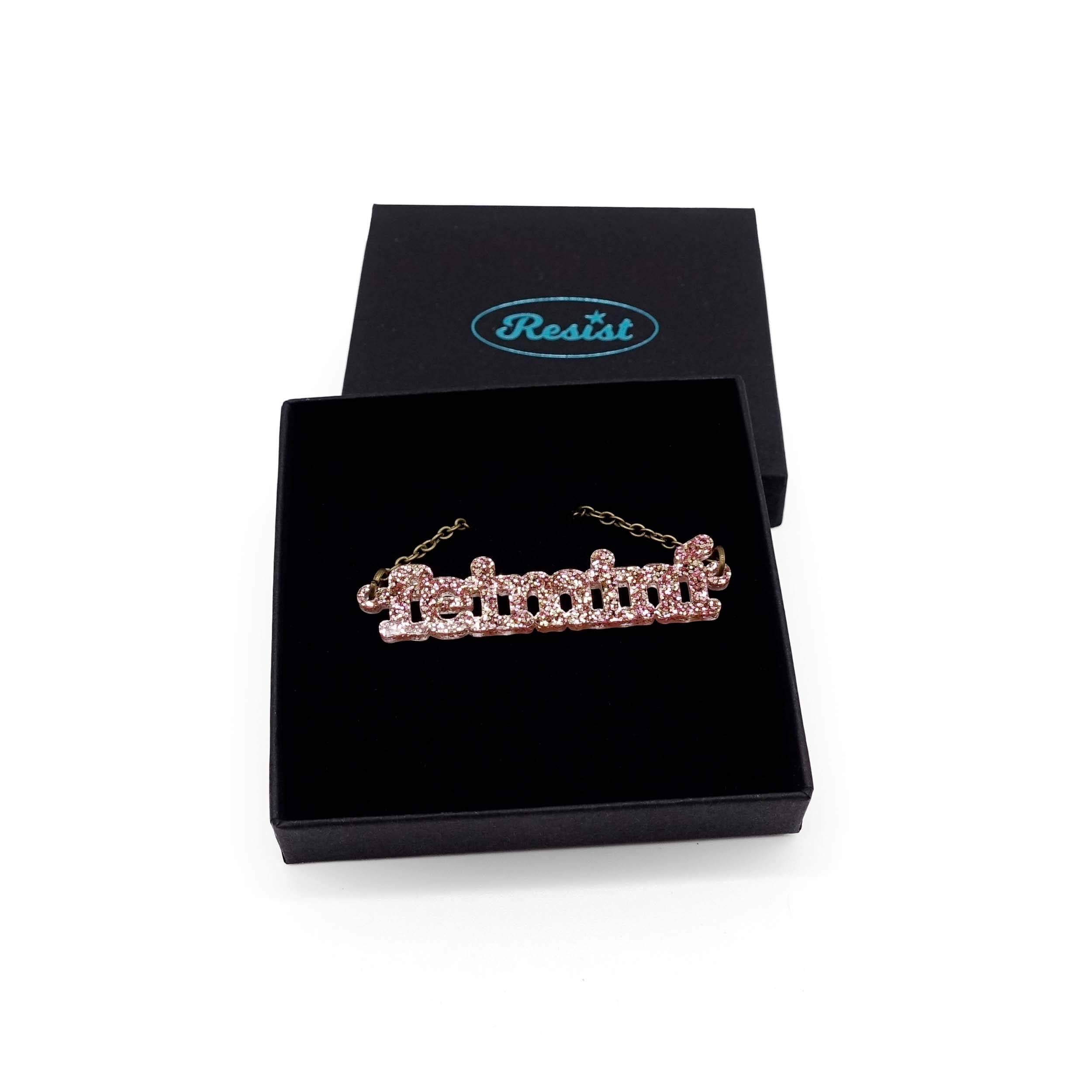 Irish Gaelic Feiminí necklace in rose glitter, shown in a Wear and Resist gift box.