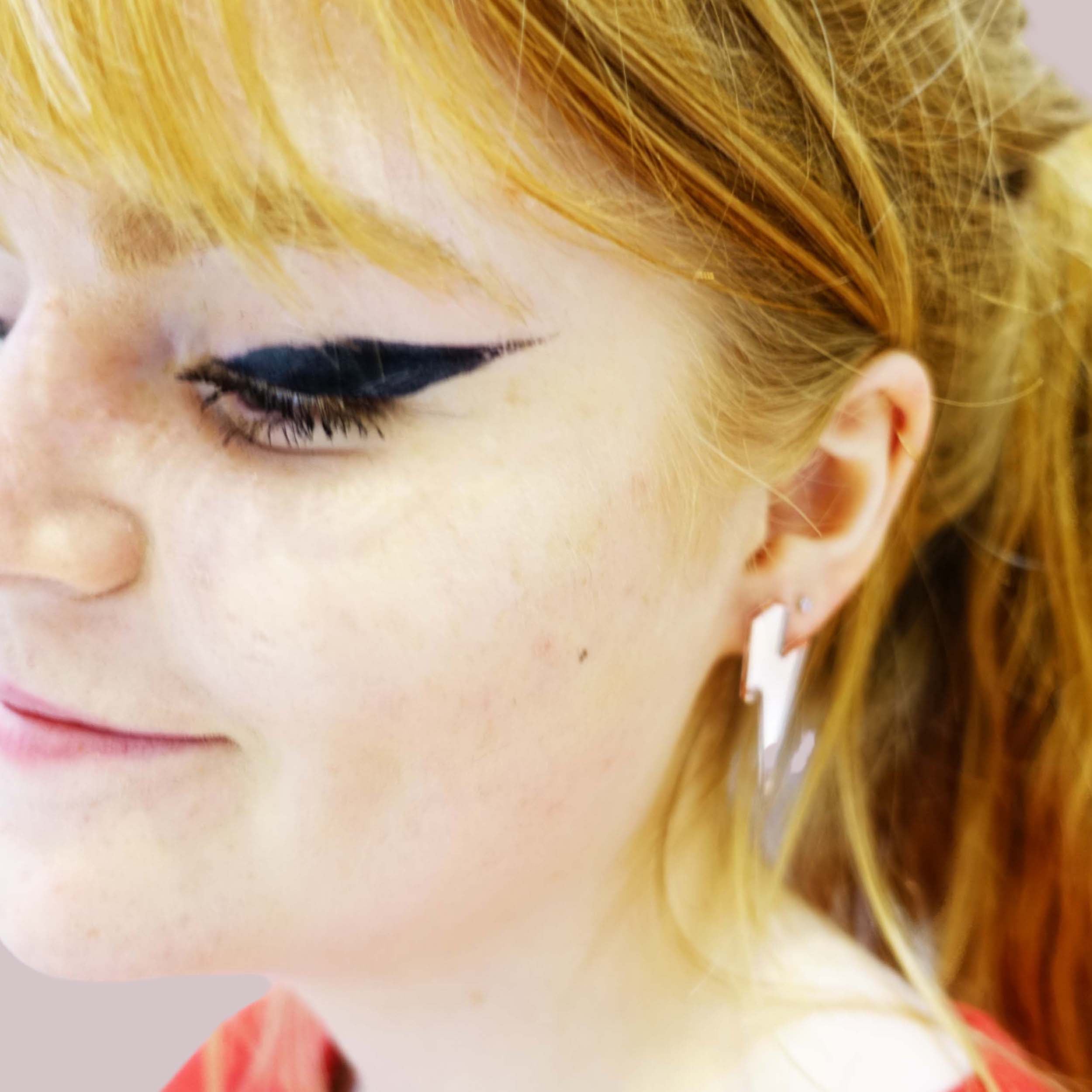 Eliza wears medium Lightning Bolt earrings in rose gold mirror.