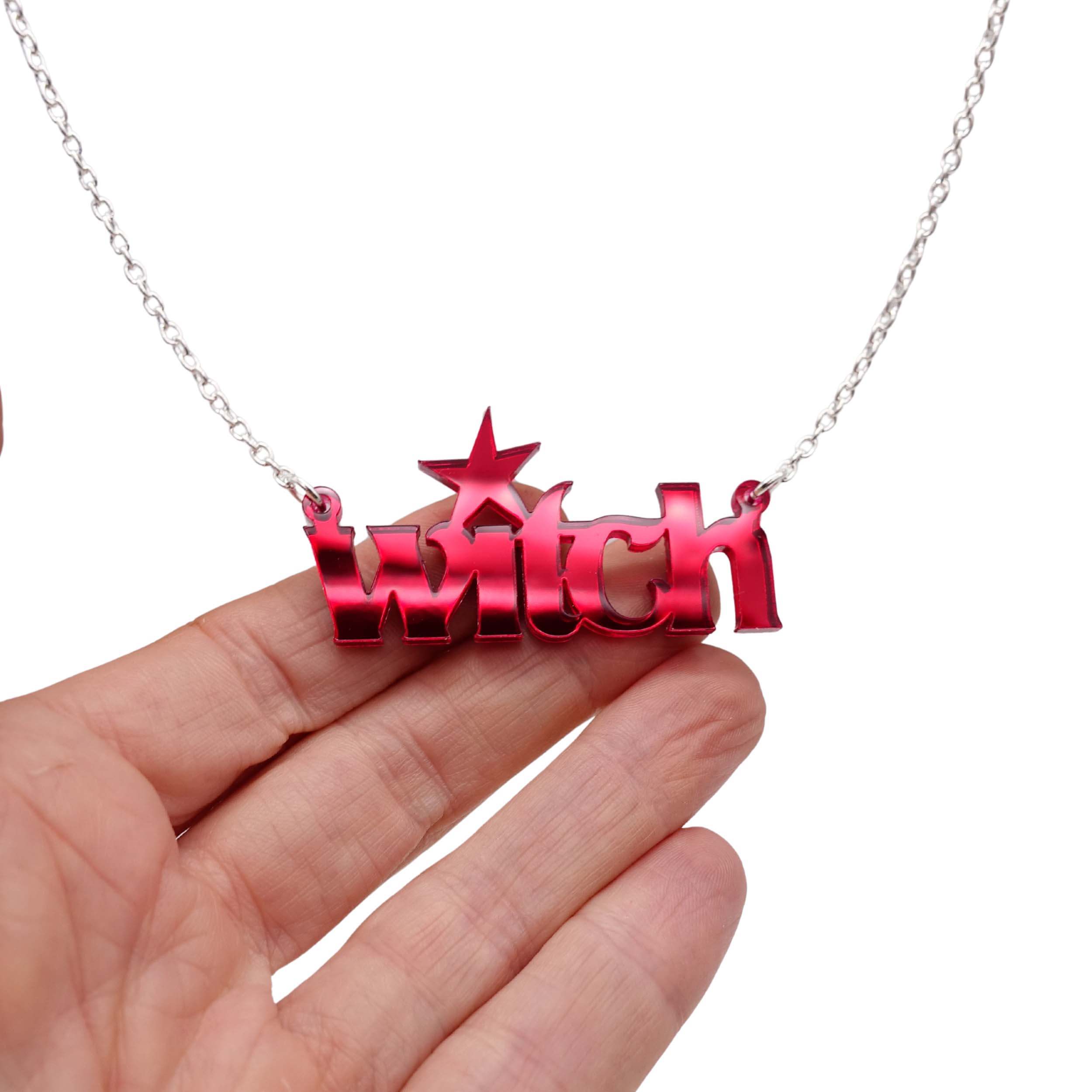 Witch necklace in ruby red mirror shown hanging against a white background with my hand for size.
