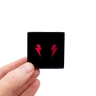 Tiny Lightning Bolt earrings in ruby mirror, shown held up in a small Wear and Resist gift box.