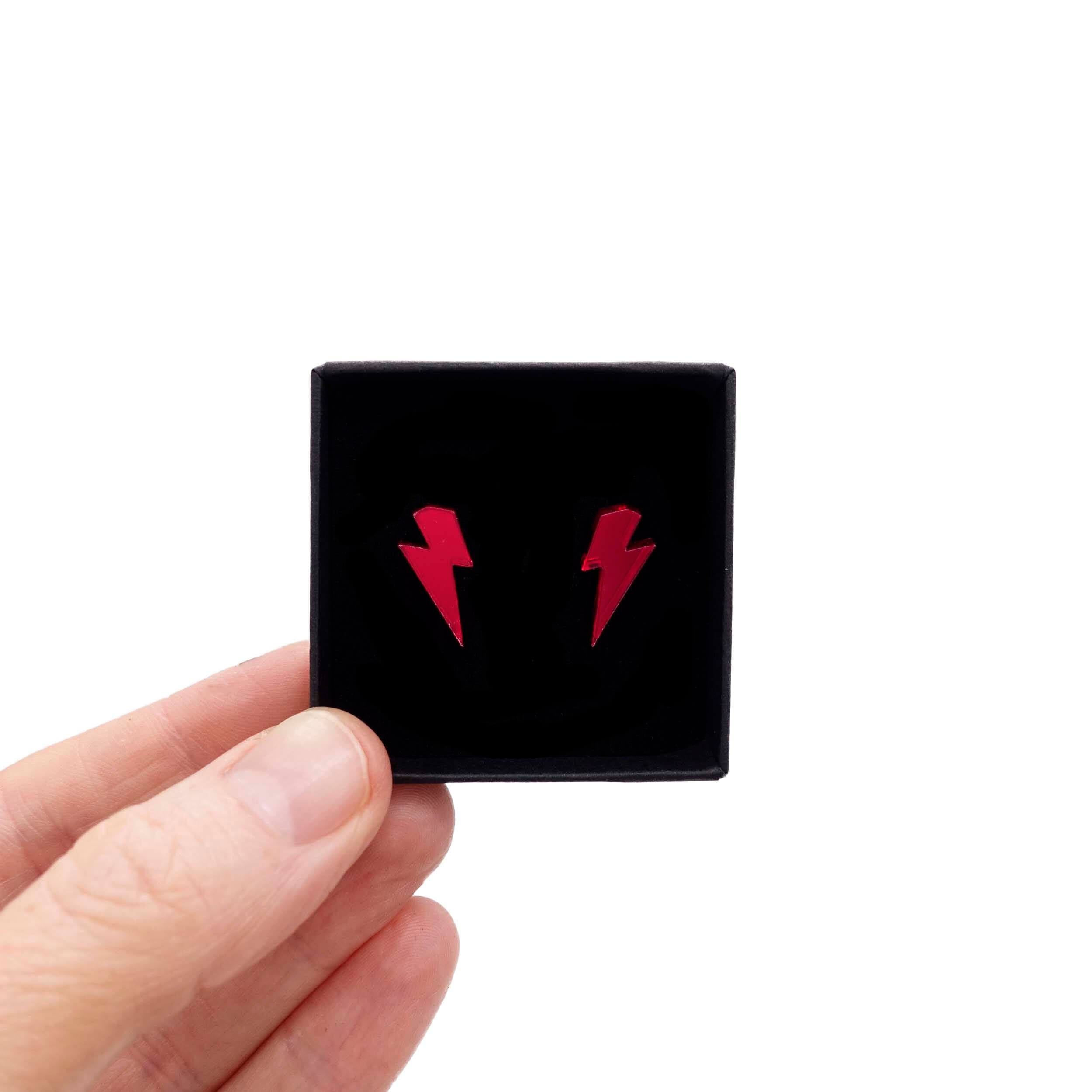 Tiny Lightning Bolt earrings in ruby mirror, shown held up in a small Wear and Resist gift box.