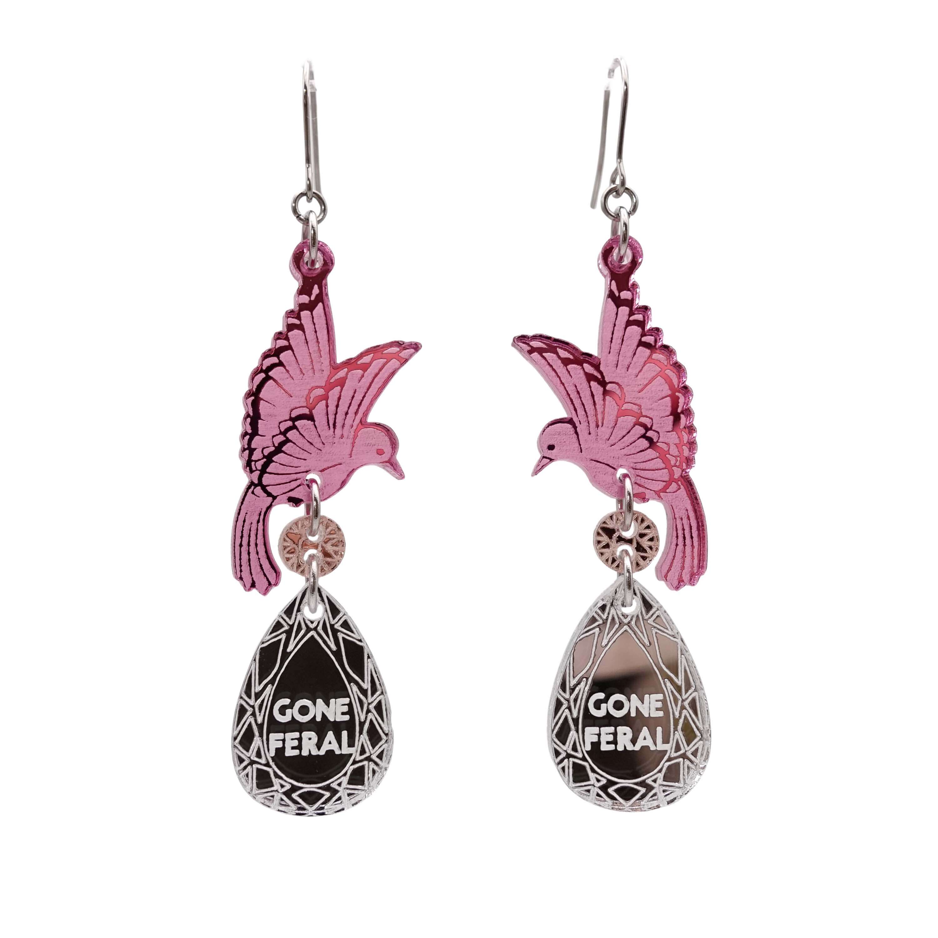 A pair of acrylic earrings with pink birds holding silver 'jewels' that say 'Gone Feral'.