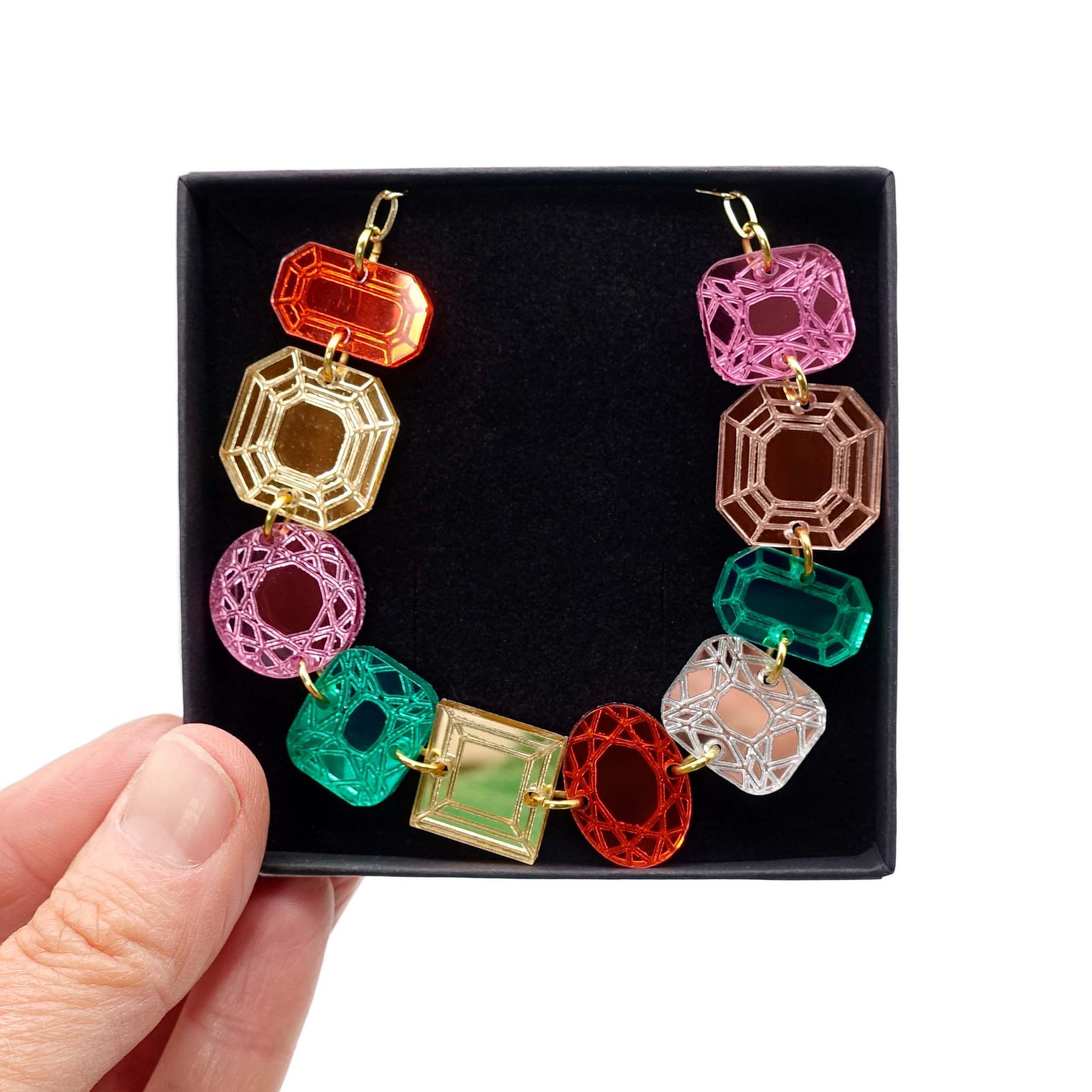 Funky Jewel mismatched gem necklace, designed by Sarah Day as part of the Austerity Jewels collection, shown held up in a  Wear and Resist gift box. £2 goes to Women for Refugee Women charity. 