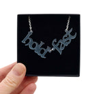 Hold Fast necklace in sea-foam shown held up in a Wear and Resist gift box.