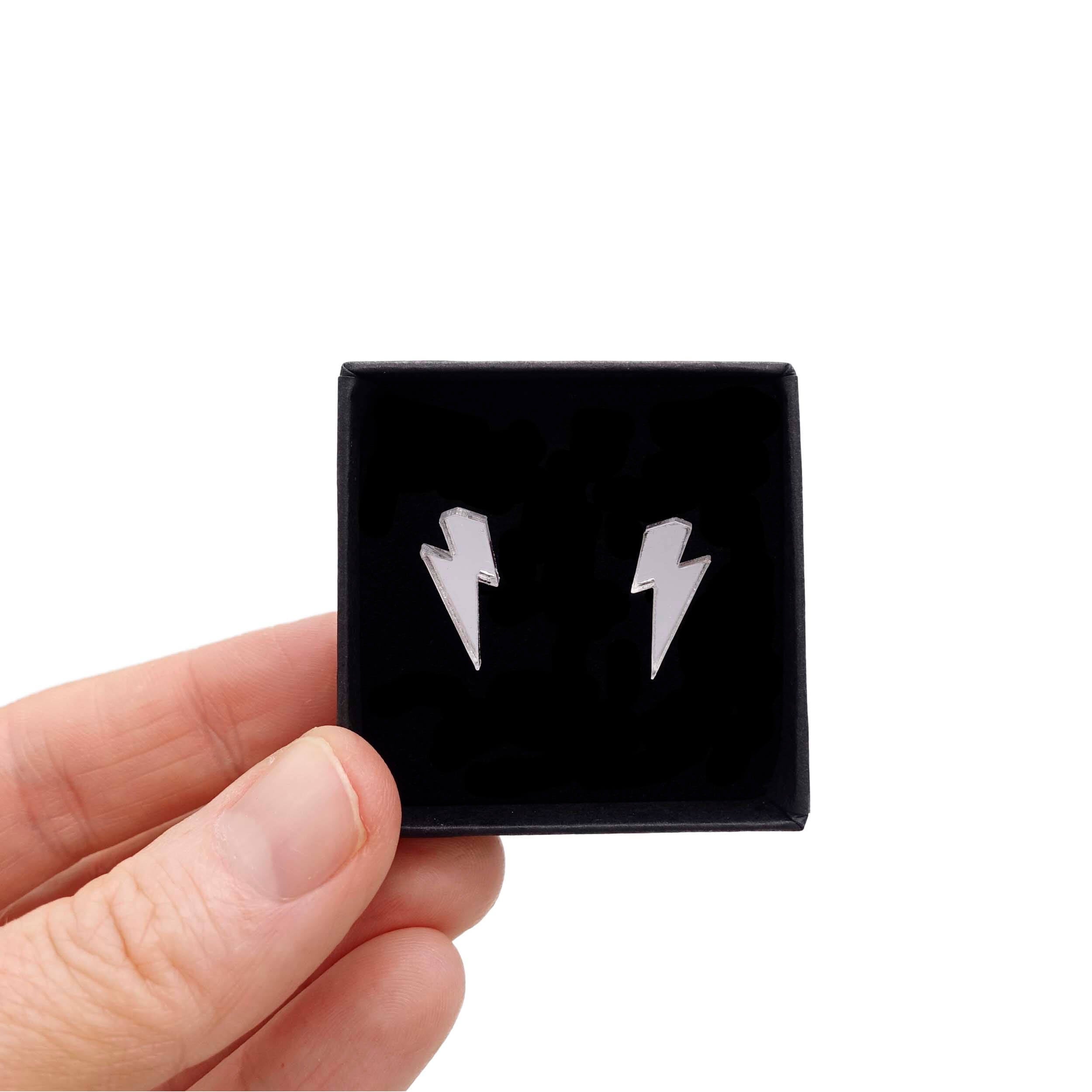 Tiny Lightning Bolt earrings in silver mirror, shown held up in a small Wear and Resist gift box.