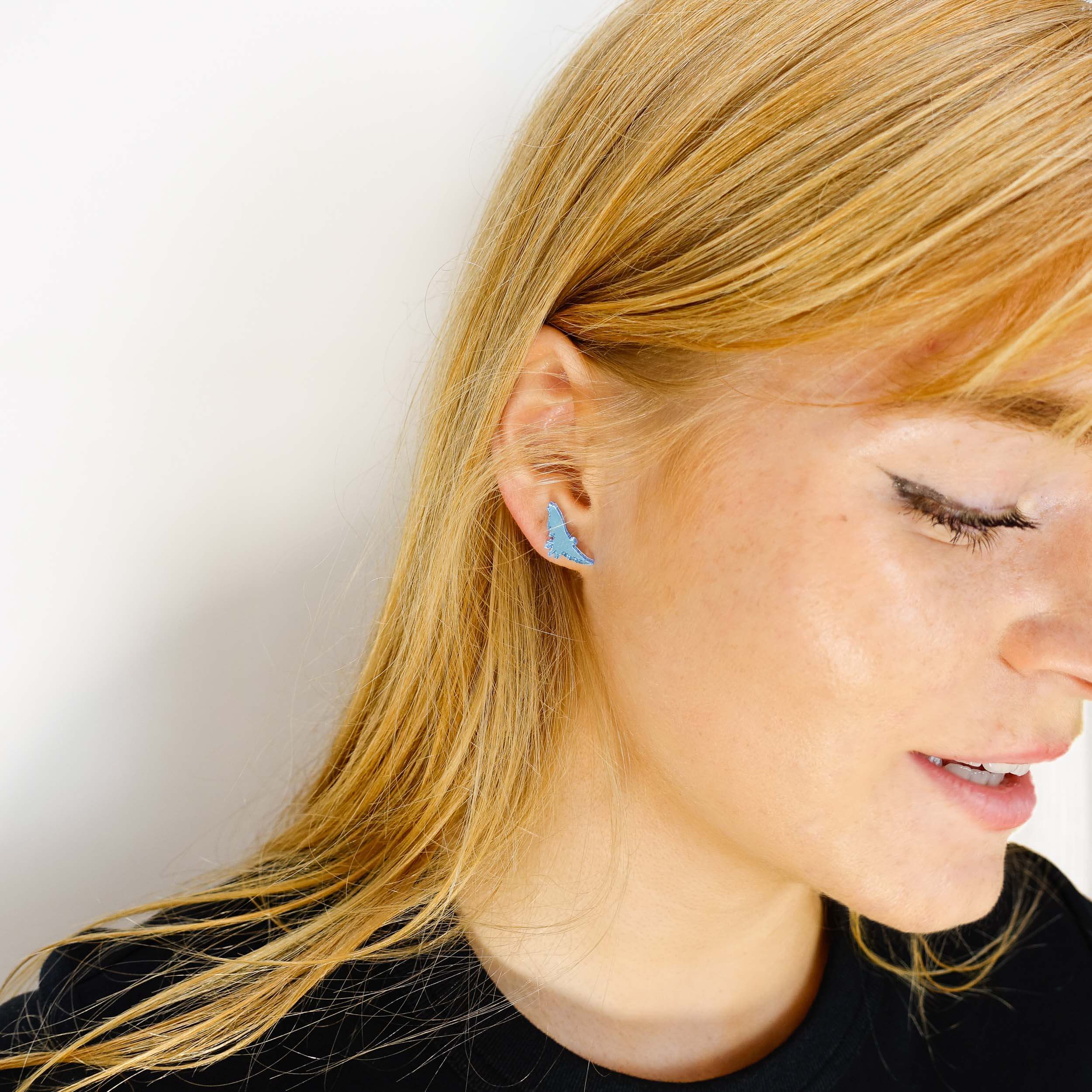 Eliza wears sky blue soaring bird stud earrings that complement the jewellery in the the Brontë Collection, designed by Sarah Day in collaboration with the Brontë Parsonage Museum.